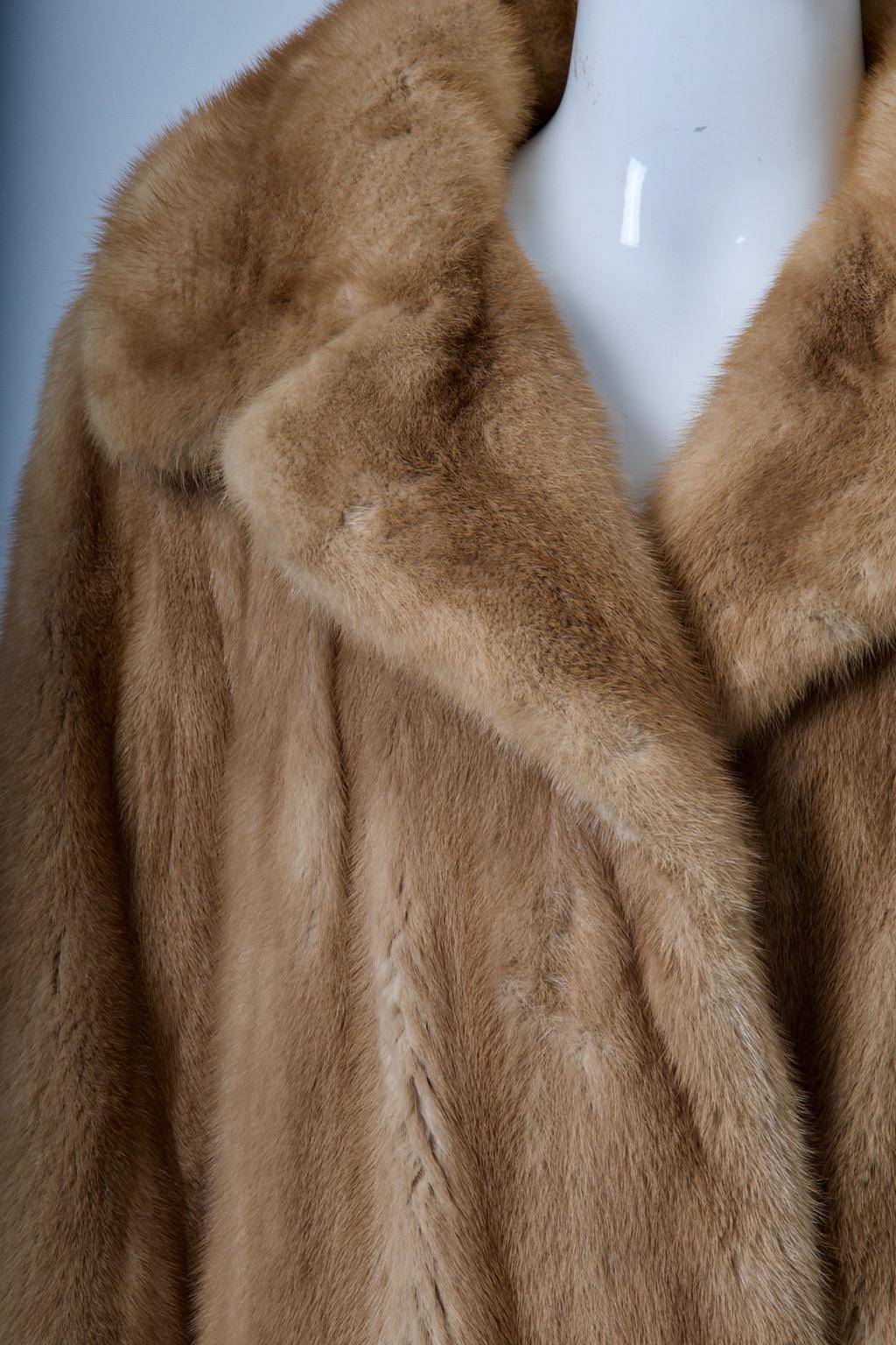 c. 1970 mink jacket in a soft golden shade features a spread collar and comes with a brown leather sash belt. One fur hook and an interior tie keep allow the jacket to be worn with or without the belt. Add your own belt for a unique look. The