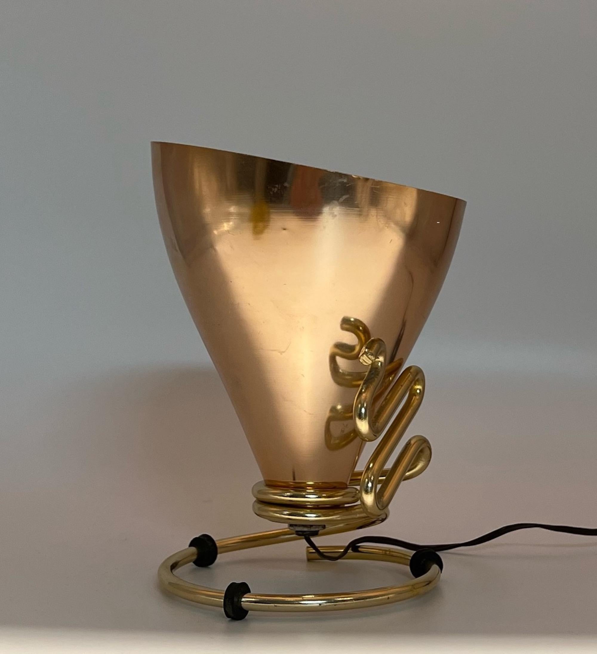 Rare and iconic lamp conceived by the creative genius of Ettore Sottsass and produced by Rinnovel.

Distinctive aluminium cone lampshade with a shining golden color, supported by a metal frame representing a snake.

This lamp was conceived to be