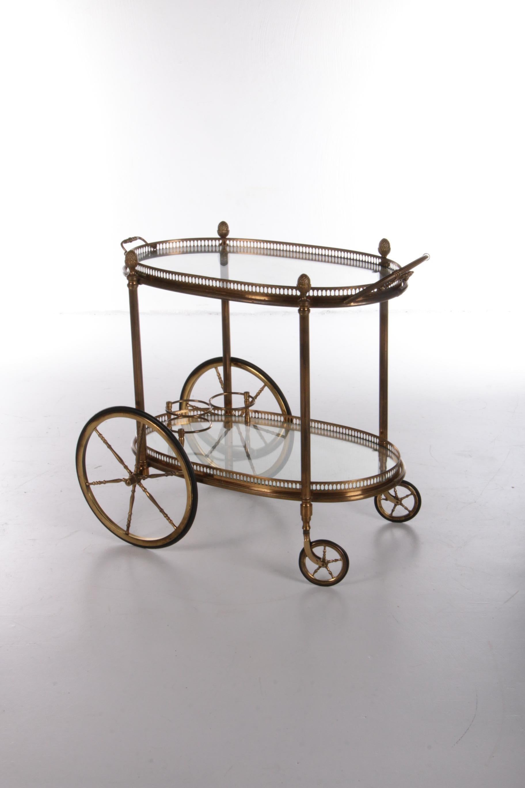Vintage golden trolley for Maison Jansen - 1960s

Brass serving trolley/tea trolley vintage with two layers.

Nice oval in shape with a brass frame and glass plates. The top tray is removable and can also be used as a tray.

Still in top