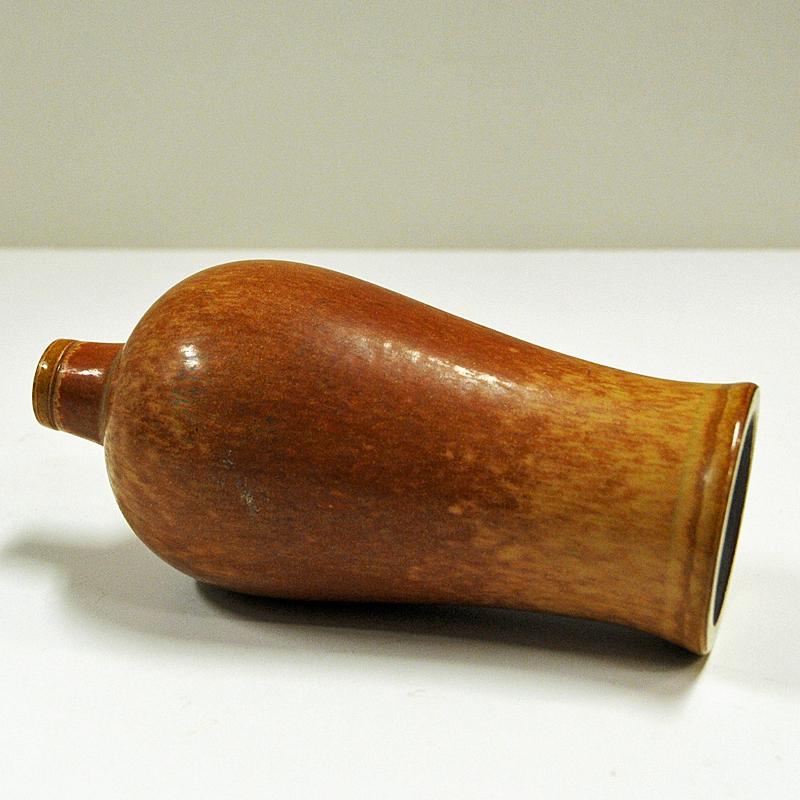 Rustic and practical midcentury stoneware vase by Gunnar Nylund for Rörstrand, Sweden, 1950s. Lovely brown patterned colors. Measures: H 16 cm., D 7 cm.
Glazed bronze elegant finish. Signed with GN Sverige. R for Rörstrand. Great patina and good