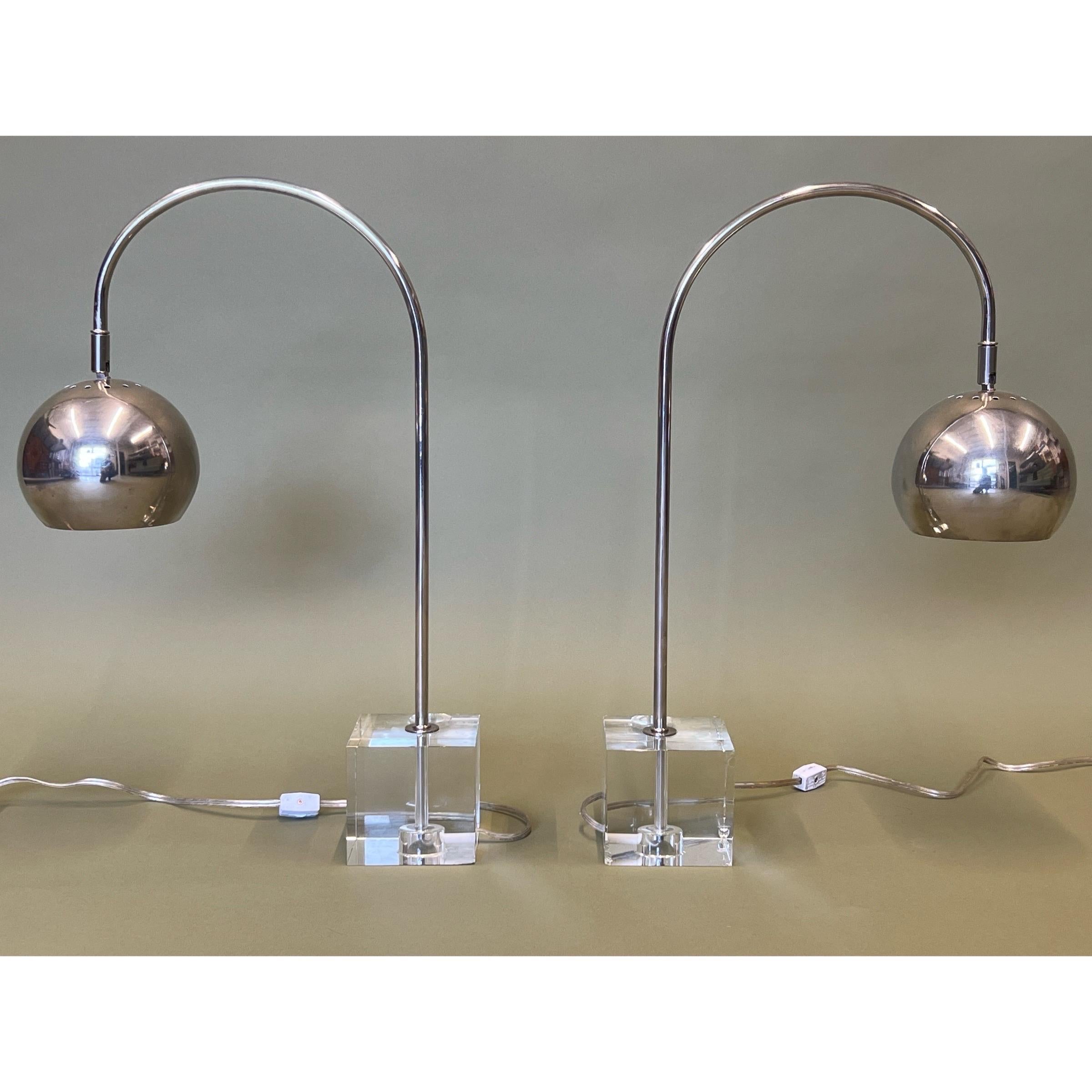Pair of vintage lamps made by Drexel Heritage. This pair models the iconic arch lamp style in miniature form. The square bases are made lucite, therefore are transparent. The gooseneck stem and eyeball shade are chrome. The eyeball shade does adjust