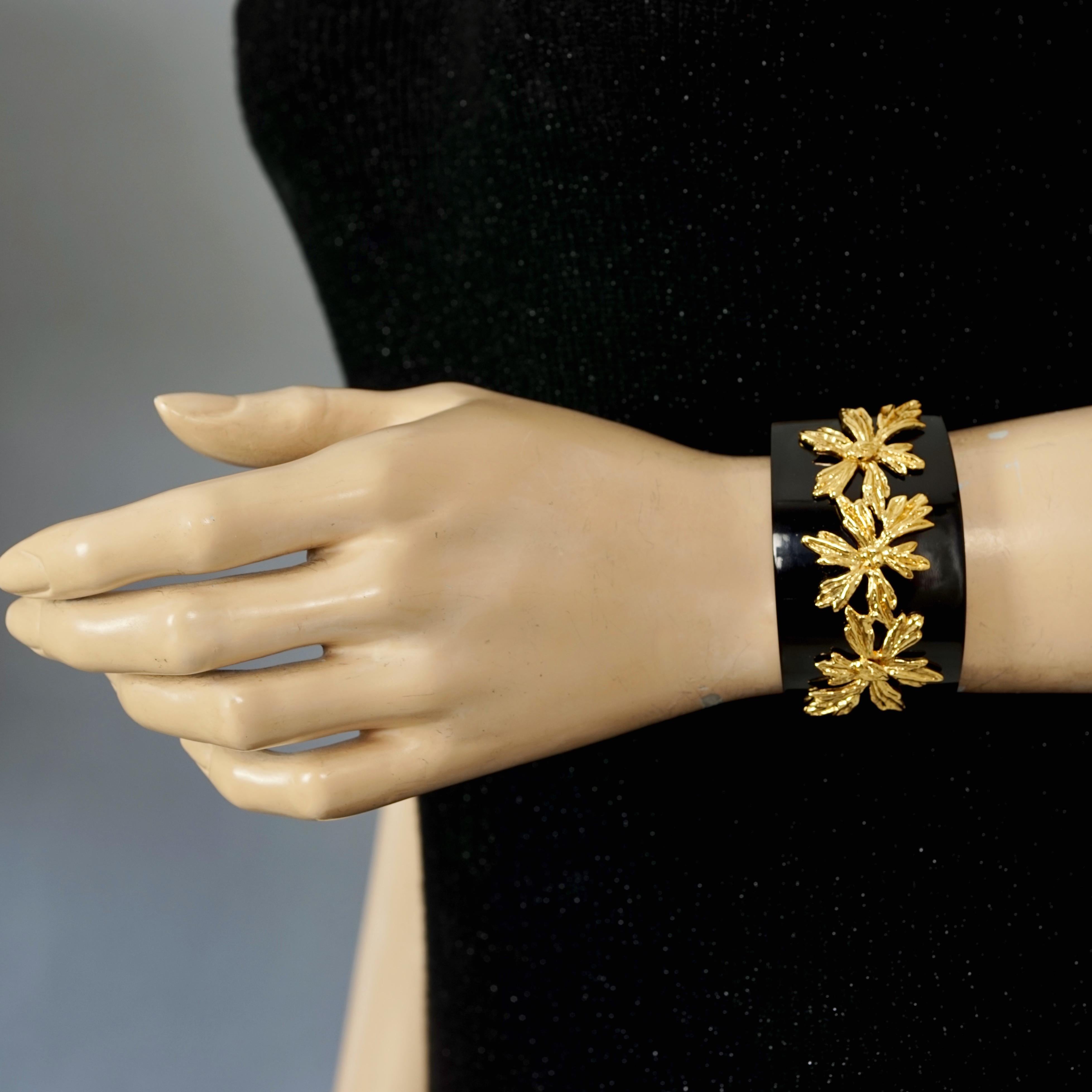 Vintage GOOSSENS PARIS Gilt Flower Overlay Black Acrylic Cuff Bracelet

Measurements:
Height: 1.57 inches (4 cm)
Inner Circumference: 6.30 cm (16 cm) opening included

Features:
- 100% Authentic GOOSSENS PARIS.
- Black acrylic bracelet with gilt