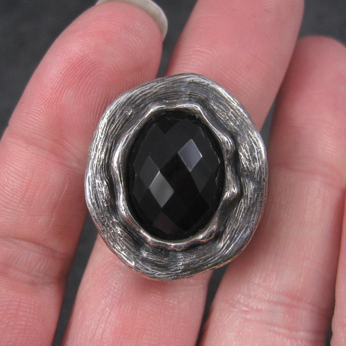 This gorgeous ring definitely makes a statement.
It boasts a large faceted oval onyx set in a textured heavy sterling setting.

The face of the ring measures 15/16 by 1 1/16th inches.
The ring is a size 6.

Marks: 925, Thailand, CID.

It is in