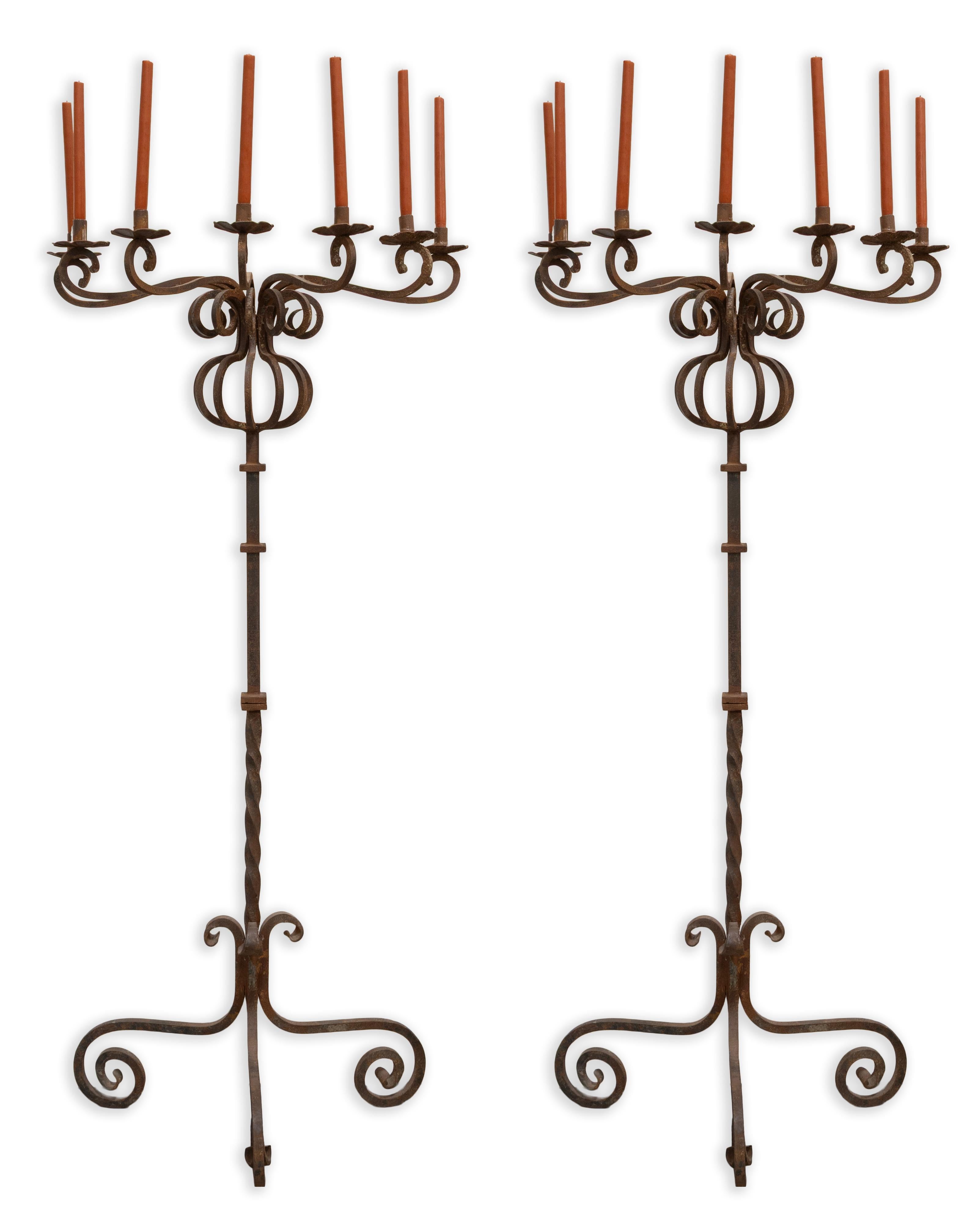 Elevate your interior with this dramatic pair of vintage Gothic-style wrought iron candelabras. Expertly hand-forged, each piece stands tall with an ornate silhouette, featuring gracefully twisted stems and elegant scrollwork at the base for added