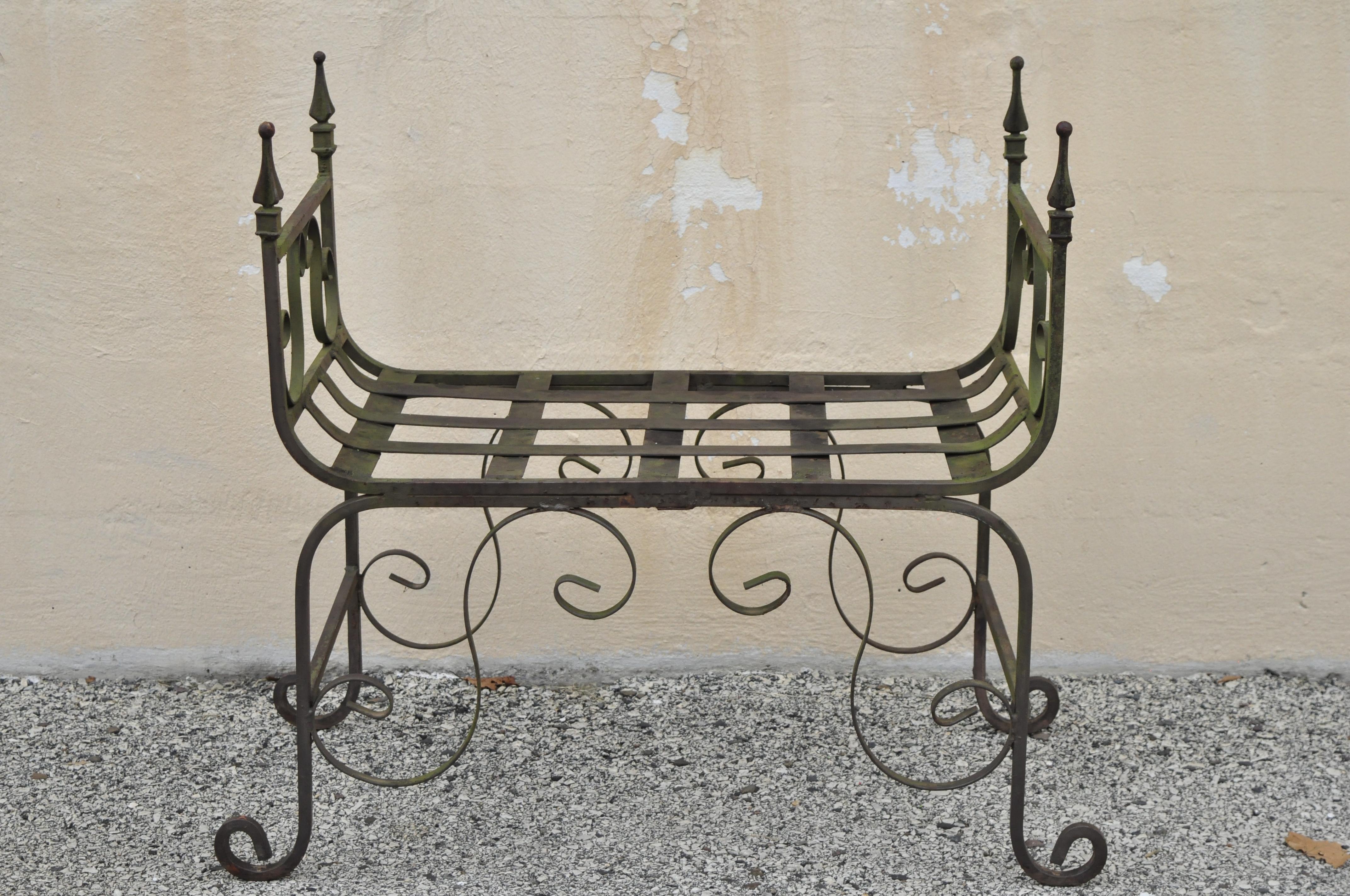 Vintage Gothic wrought iron Curule scrollwork distressed green bench with finials. Item features pointed finials, scrolling frame, lattice seat, wrought iron construction, great style and form, circa mid to late 20th century. Measurements: 30.5