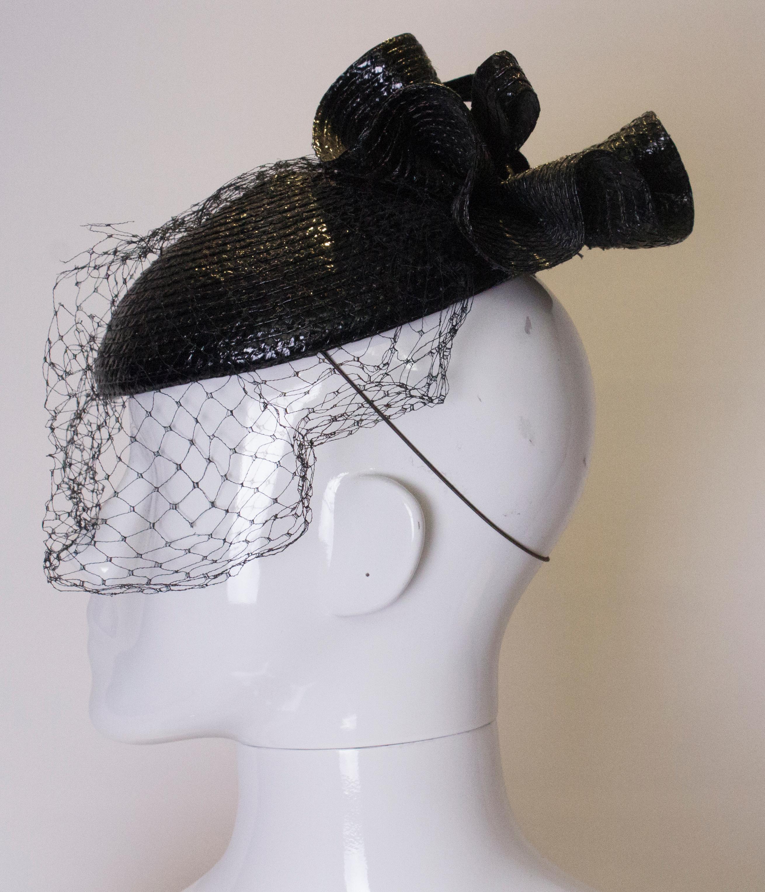 A chic vintage hat by Graham Smith for Kangol, sold at Harrods. It has a decorative straw bow and net veil . The inner circumference is 18''.