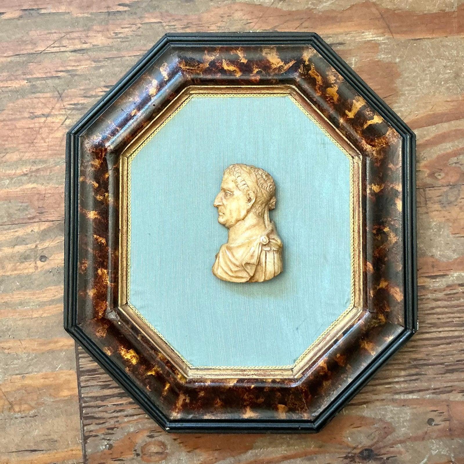 Wir präsentieren ein elegantes dekoratives Kunstwerk im Vintage-Stil mit einer goldenen Büste im neoklassischen Stil vor einem gedämpften blaugrauen Hintergrund in einem achteckigen Rahmen mit Schildpatt-Finish. Dieses Stück fängt auf wunderbare