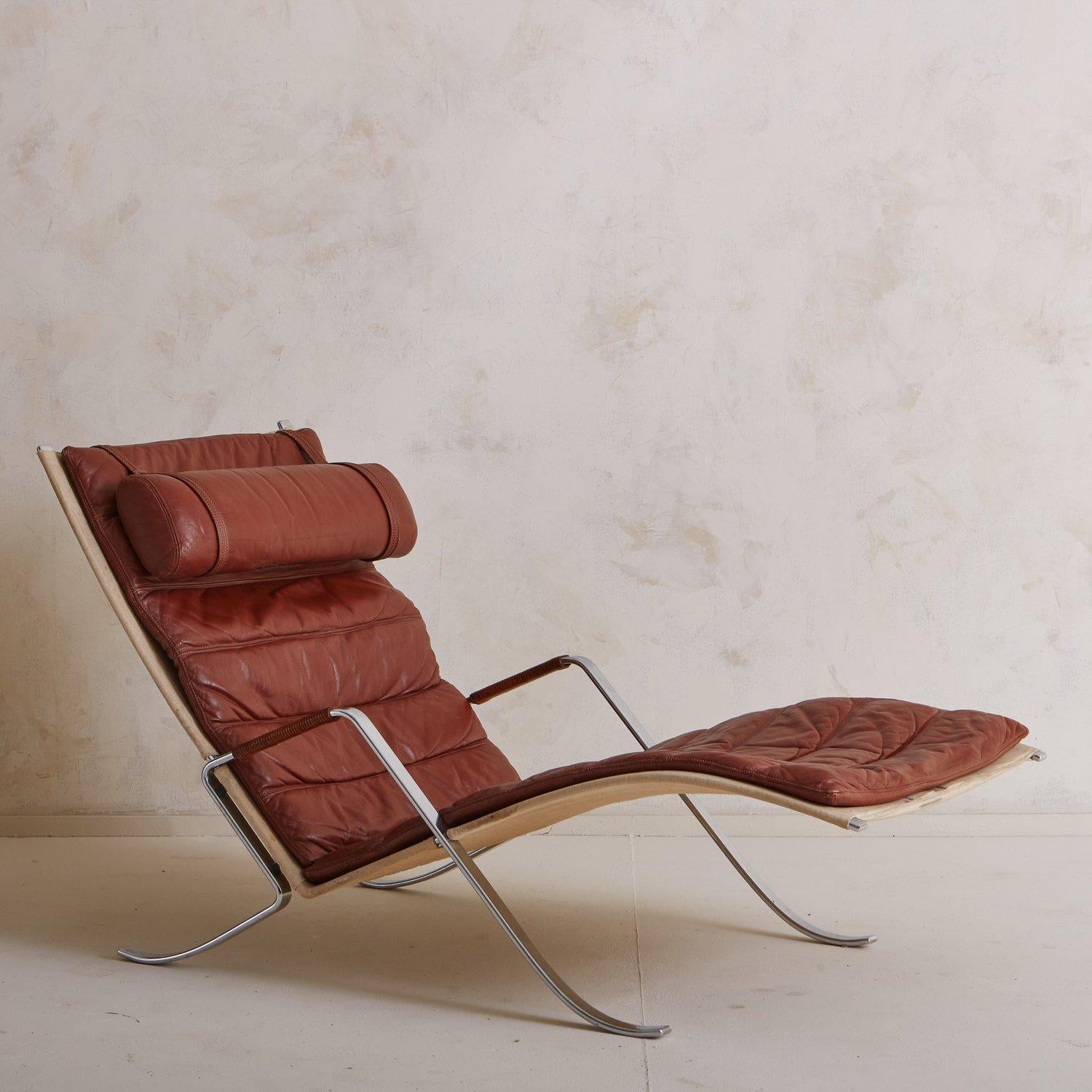 A vintage grasshopper arm chair by Preben Fabricius and Jørgen Kastholm for Kill International. This sculptural lounge features a beautiful patinated leather cushion with channeled details and a detachable headrest. It has a polished chrome plated