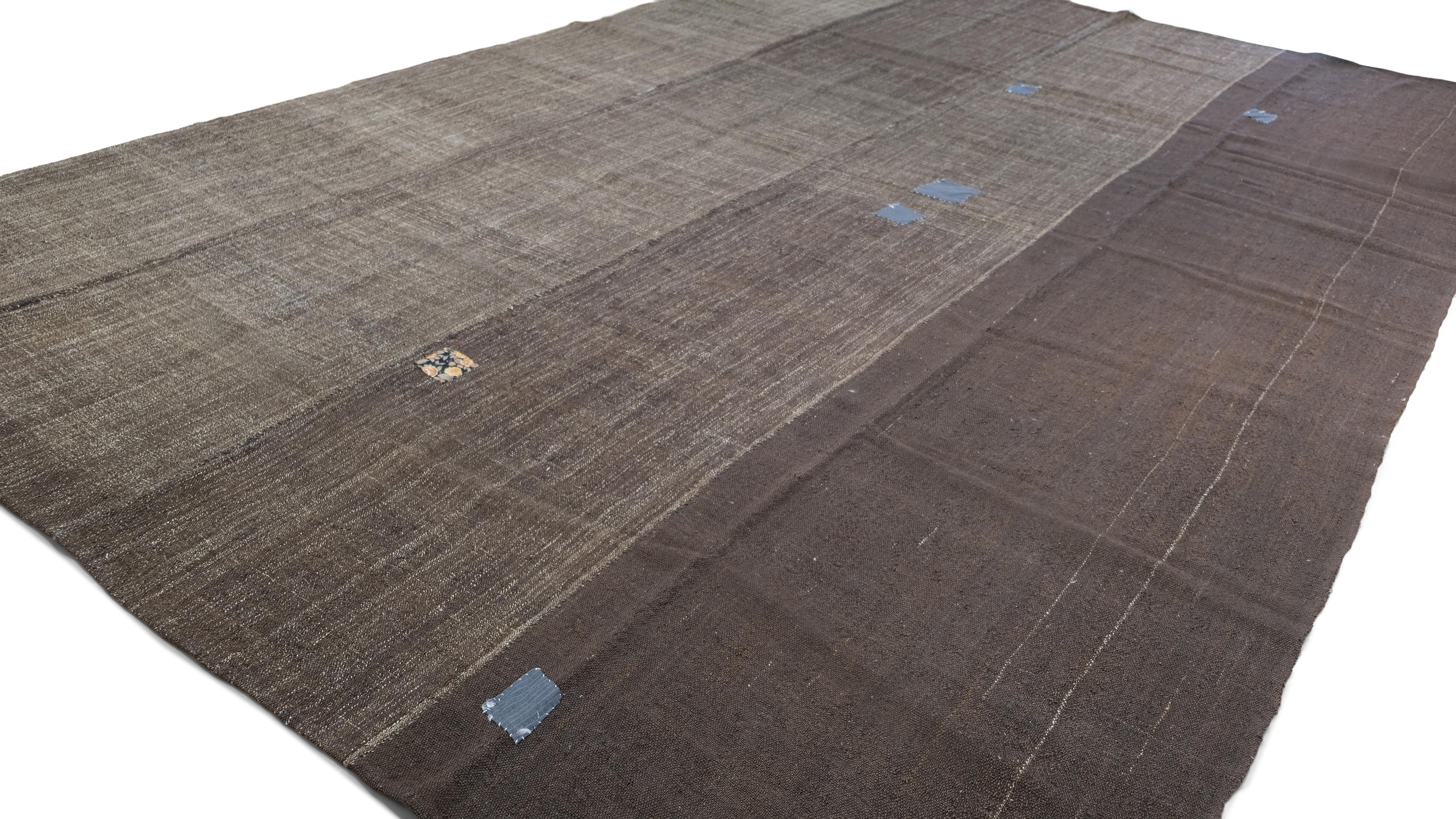 This authentic hand-woven goat hair kilim showcases the artistry of traditional tribal craftsmanship, featuring a bold striped composition, natural variations, and timeworn patch repairs that enhance its wabi-sabi aesthetic. Made from undyed goat