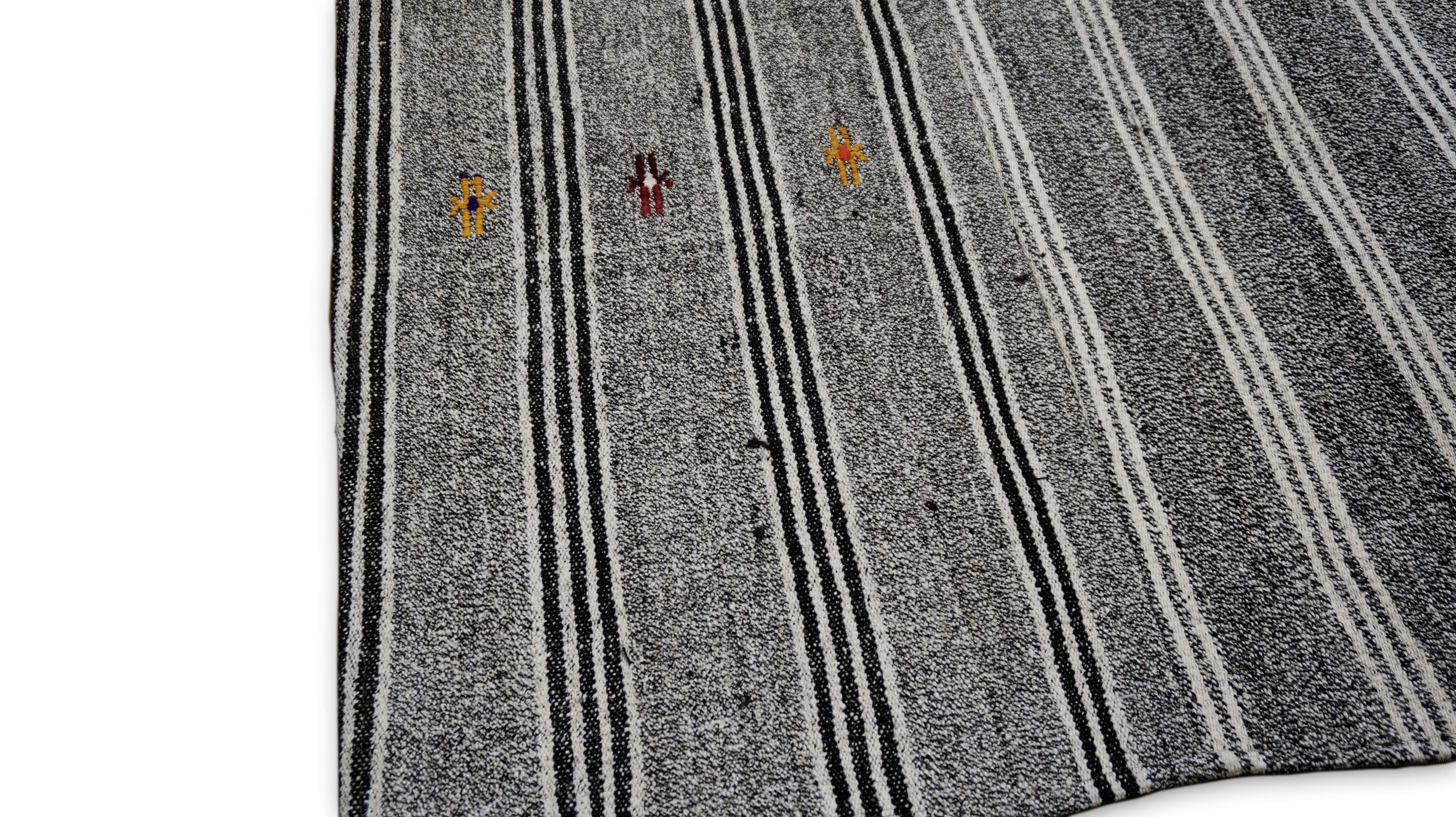 Dieser einzigartige Kilim-Teppich aus Wolle und Hanf zeichnet sich durch ein auffälliges Streifenmuster in natürlichen Grau-, Rot-, Gelb-, Weiß- und Anthrazittönen aus. Der mit traditionellen Techniken handgewebte Teppich zeichnet sich durch
