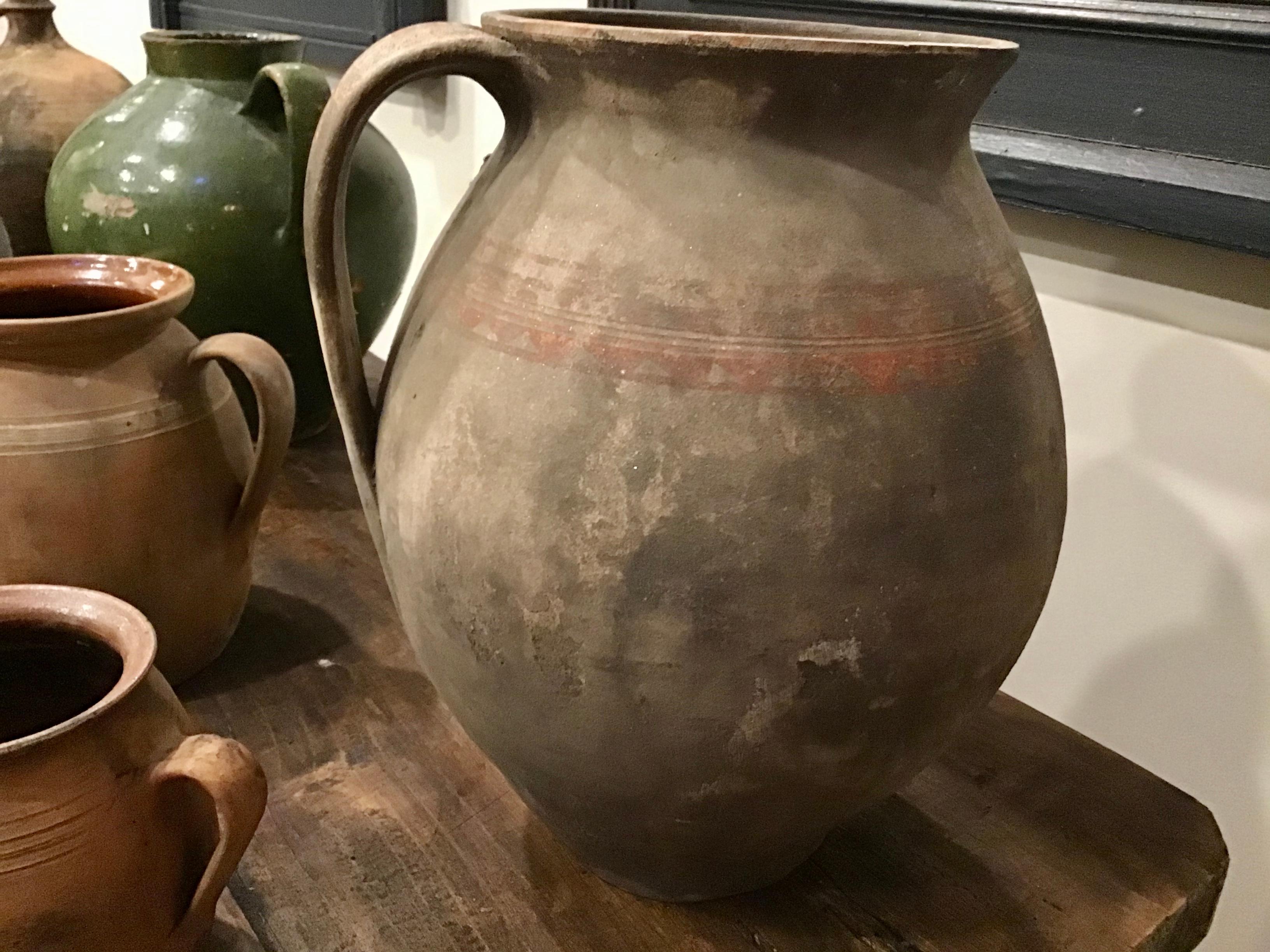 Single handle, unglazed vintage gray French jug primarily used to transport water and other liquids. Original orange stripes around jug still visible with aged salt deposits.
  