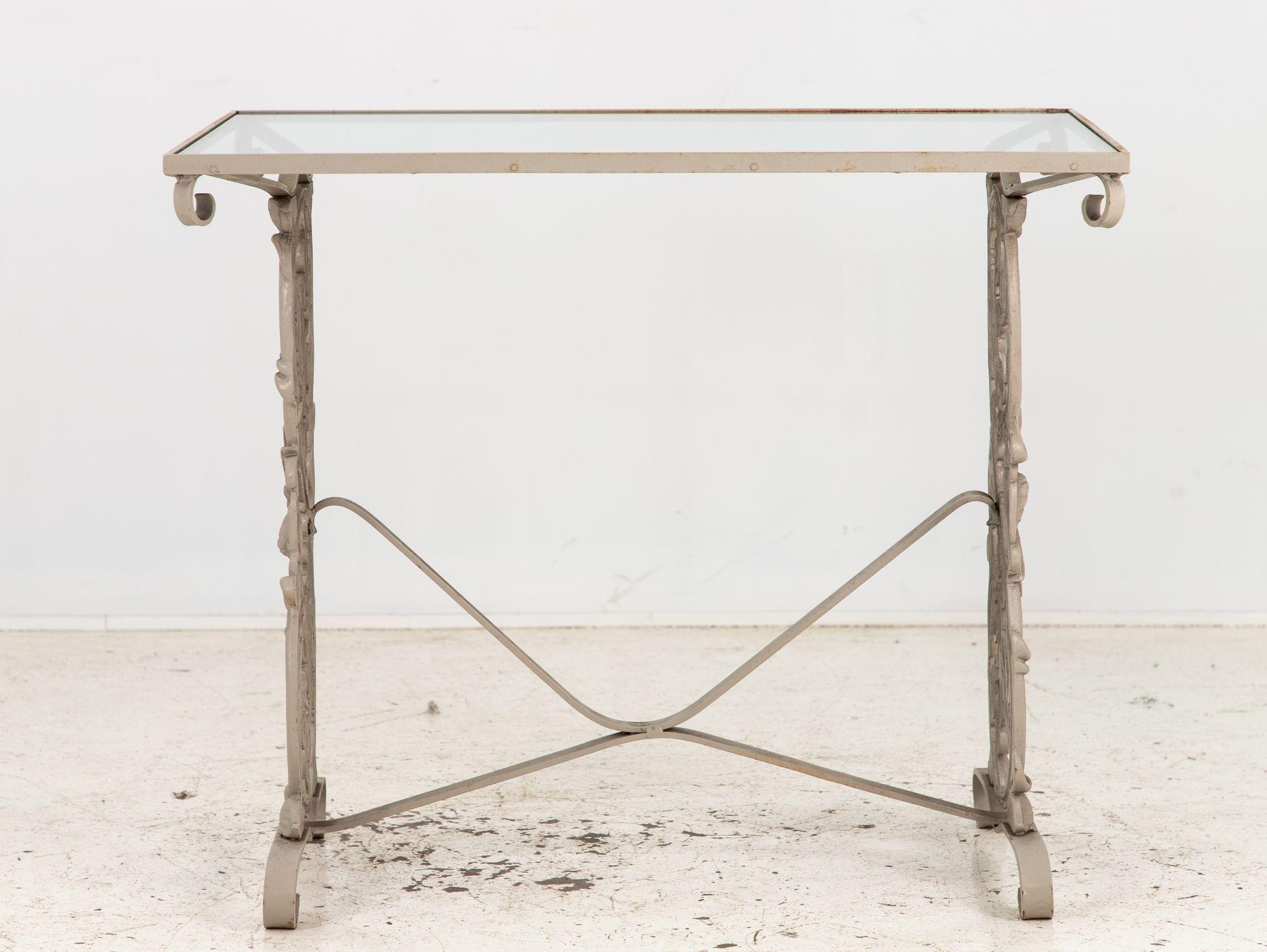 Crafted in the late 20th century, this outdoor console exudes timeless elegance. Constructed from sturdy cast iron and adorned with a glass top, it boasts durability and style. Its trestle-style design features a captivating leaf and vine motif,