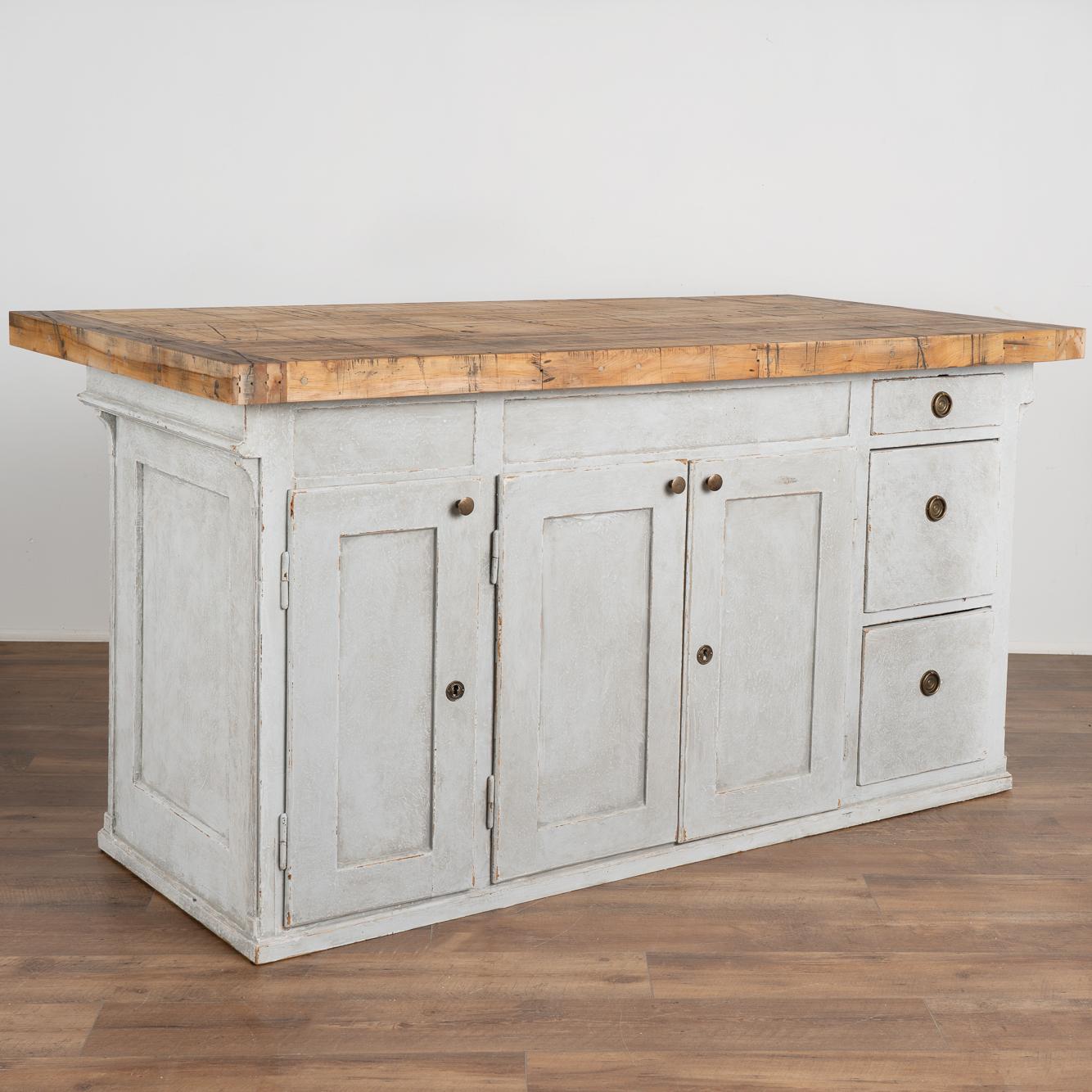 This old pine shop counter from Sweden has been given new life with a professional gray painted finish creating a fresh look for a modern kitchen island.
The top is made from old boxcar flooring (from a train); thick and heavy, it is filled with