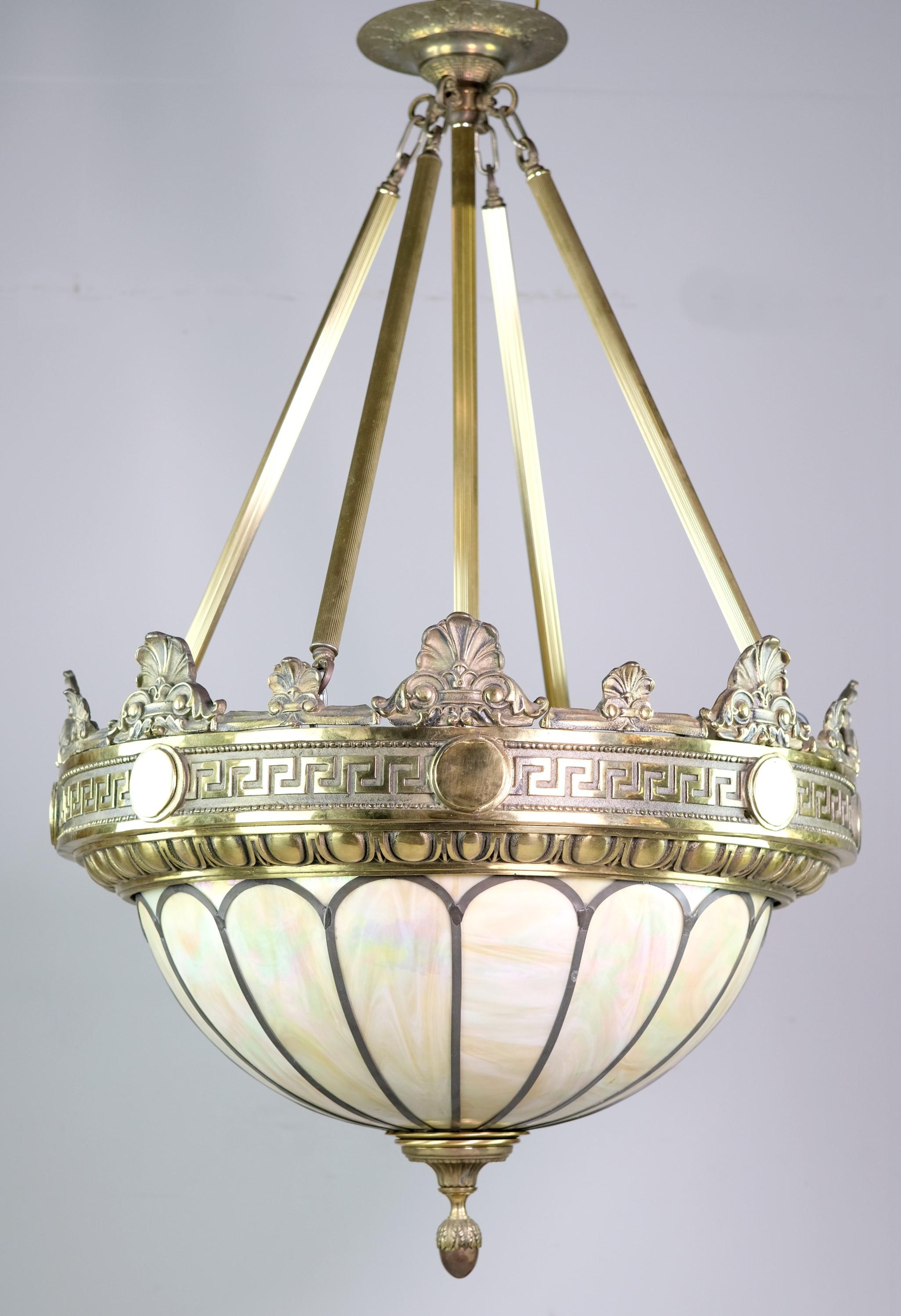 Retrieved from a famous Manhattan Hotel lobby. Solid bronze pendant light designed in a Greco Roman style with a stained glass dish shade. Solid bronze rim features an egg & dart design with floral details and shells. Bottom of light shows off an