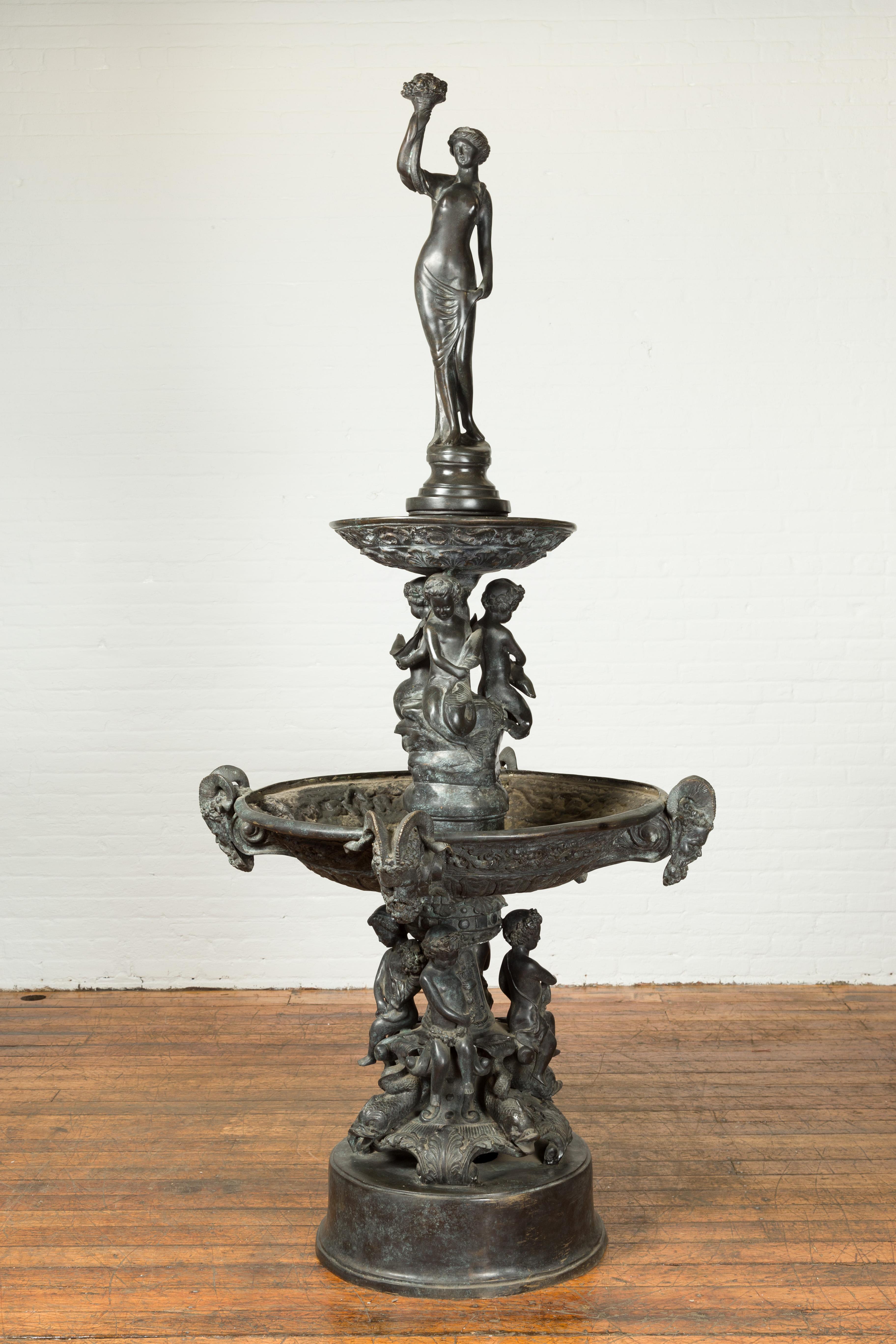 Grande fontaine de style gréco-romain en bronze coulé à la cire perdue, datant du milieu du XXe siècle, représentant une nymphe avec une corne d'abondance, des Tritons et des chérubins. Créée avec la technique traditionnelle de la cire perdue qui