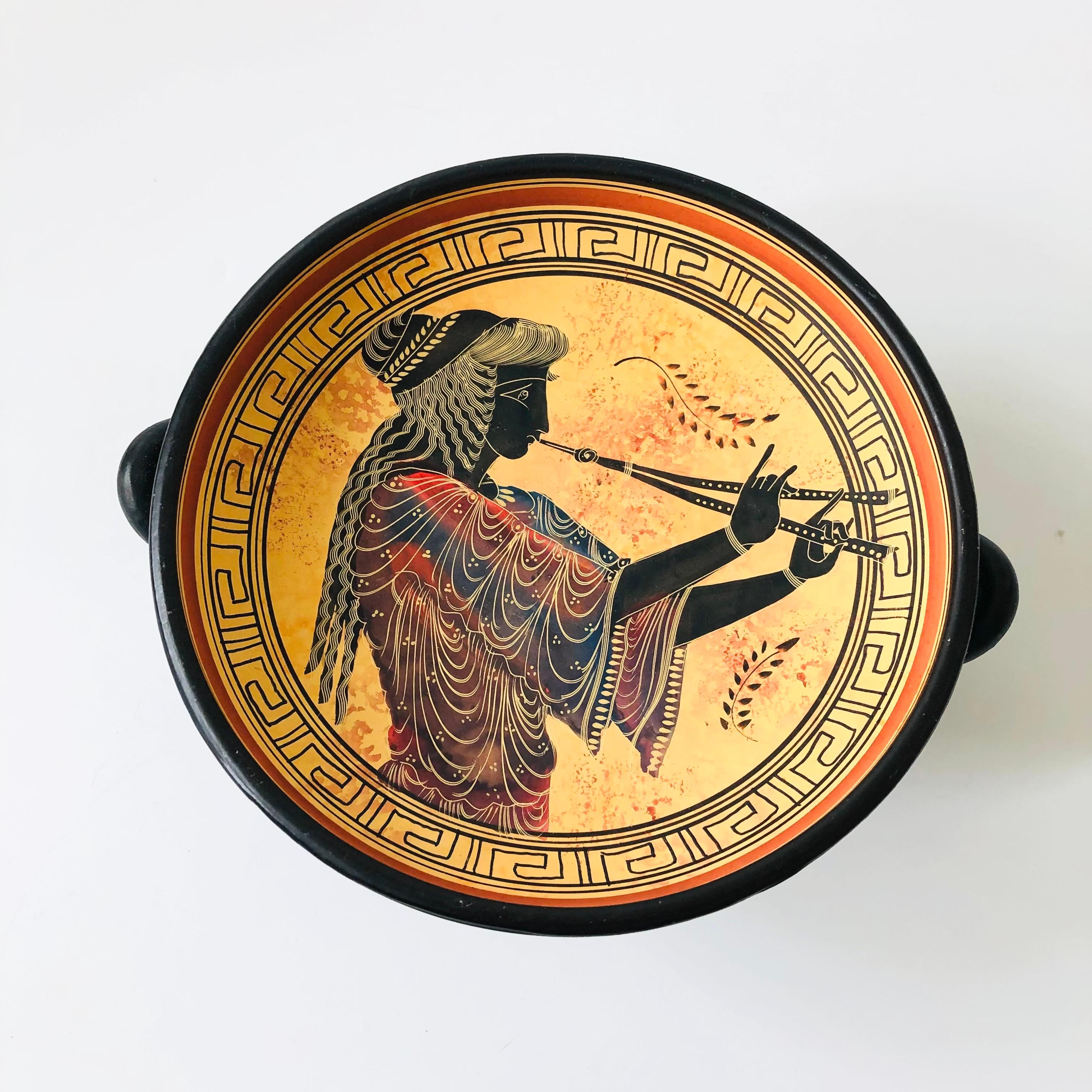 A vintage greek reproduction footed pottery bowl. Decorated with highly detailed hand painted designs throughout. Handles formed on the sides. Marked on the base.

