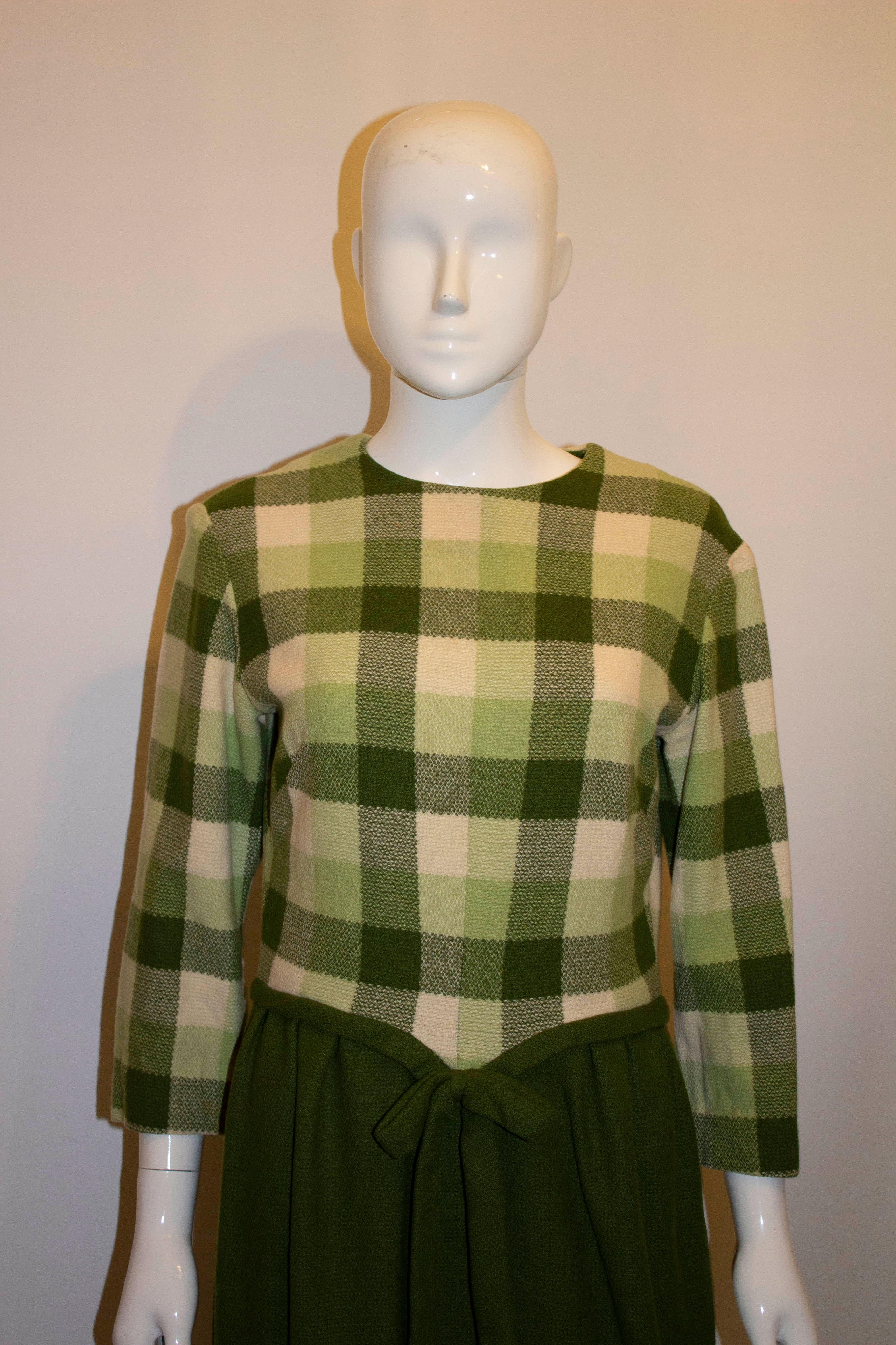 A fun and easy to wear vintage green and white day dress. The dress has a green and white check bodice /upper area with a plain green skirt. It has gathering from the waist and a nice belt detail at the front. It has a central back zip and is
