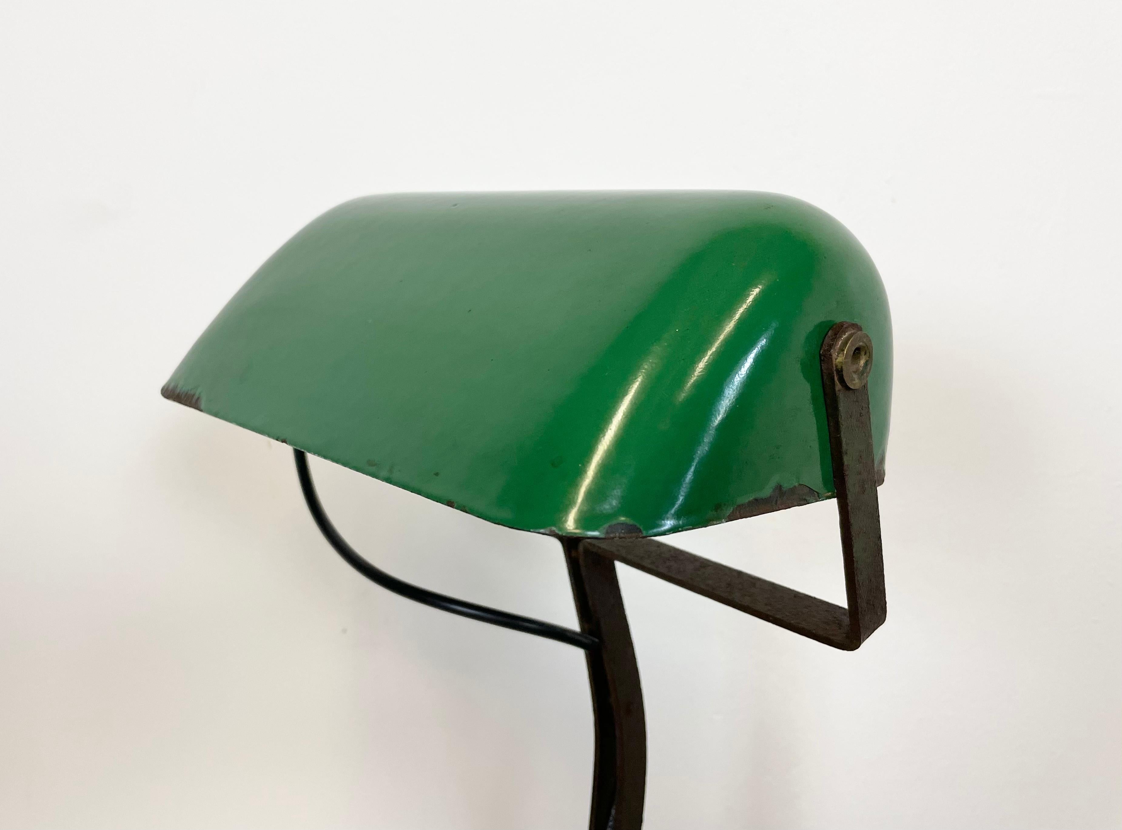 Vieille lampe de table verte fabriquée par Astral Austrian Make dans les années 1930. Il comporte une base en fonte et un abat-jour en fer émaillé vert avec intérieur blanc. La douille originale en porcelaine avec interrupteur nécessite des ampoules