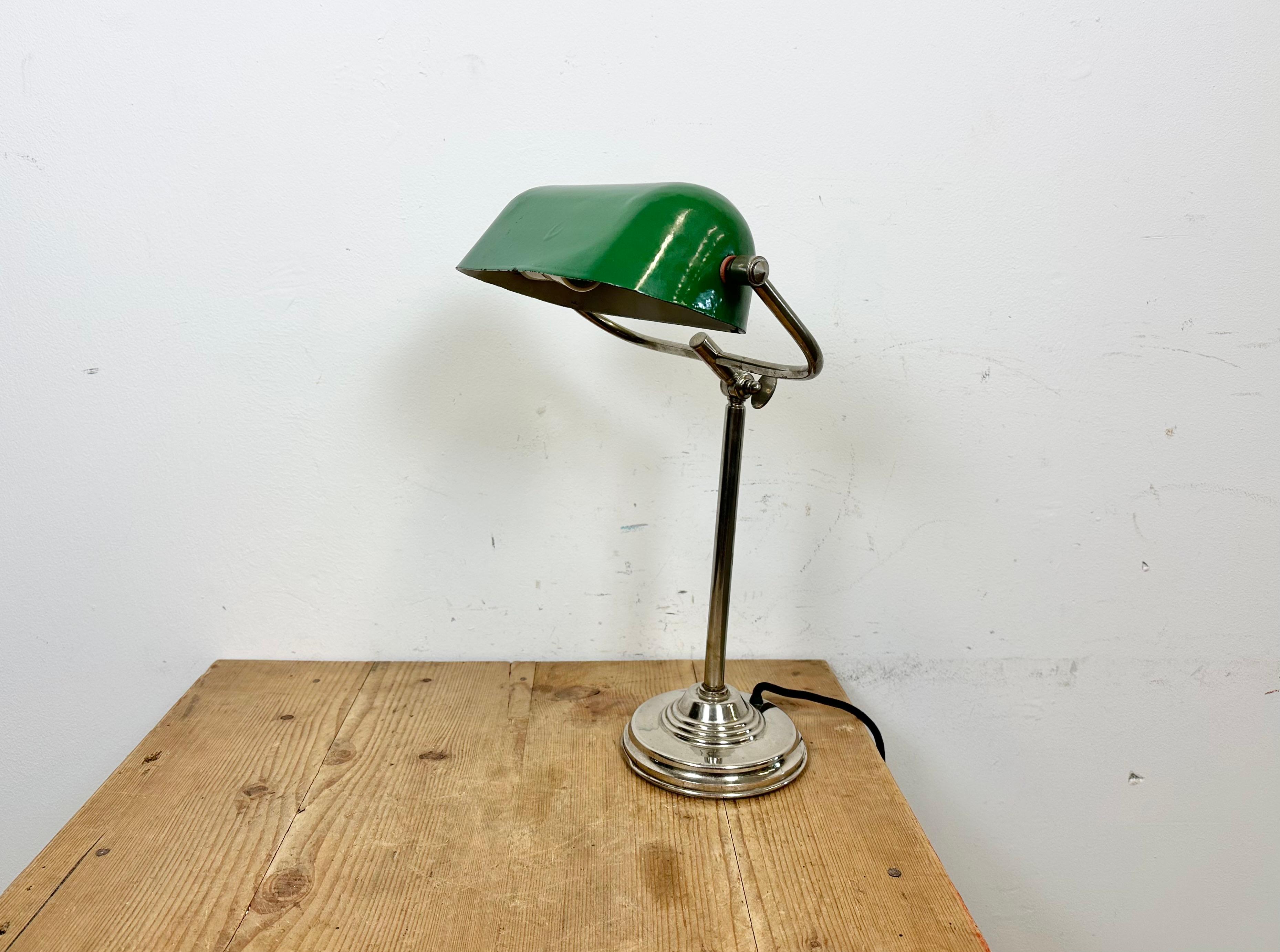 This table lamp was made in former Czechoslovakia during the 1960s. It features a green enamel shade with a white enamel interior and a chrome plated iron base and arm with adjustable joint. Original porcelain socket requires E 27/ E 26 ligh bulbs.