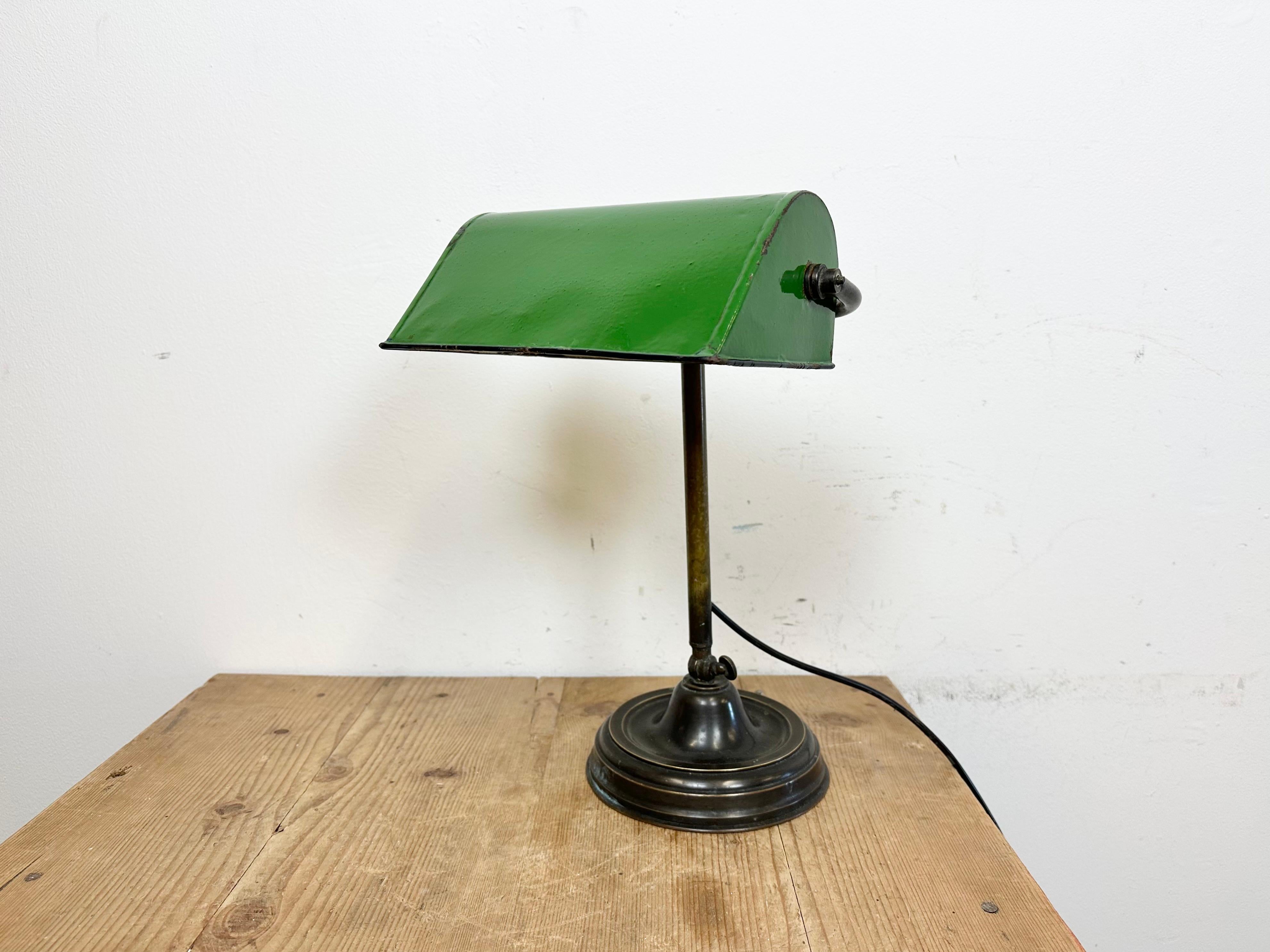 This table lamp was made in former Czechoslovakia during the 1960s. It features a green adjustable enamel shade with a white enamel interior and a brass iron base and arm with adjustable joint. The porcelain socket requires standard E 27/ E 26 ligh