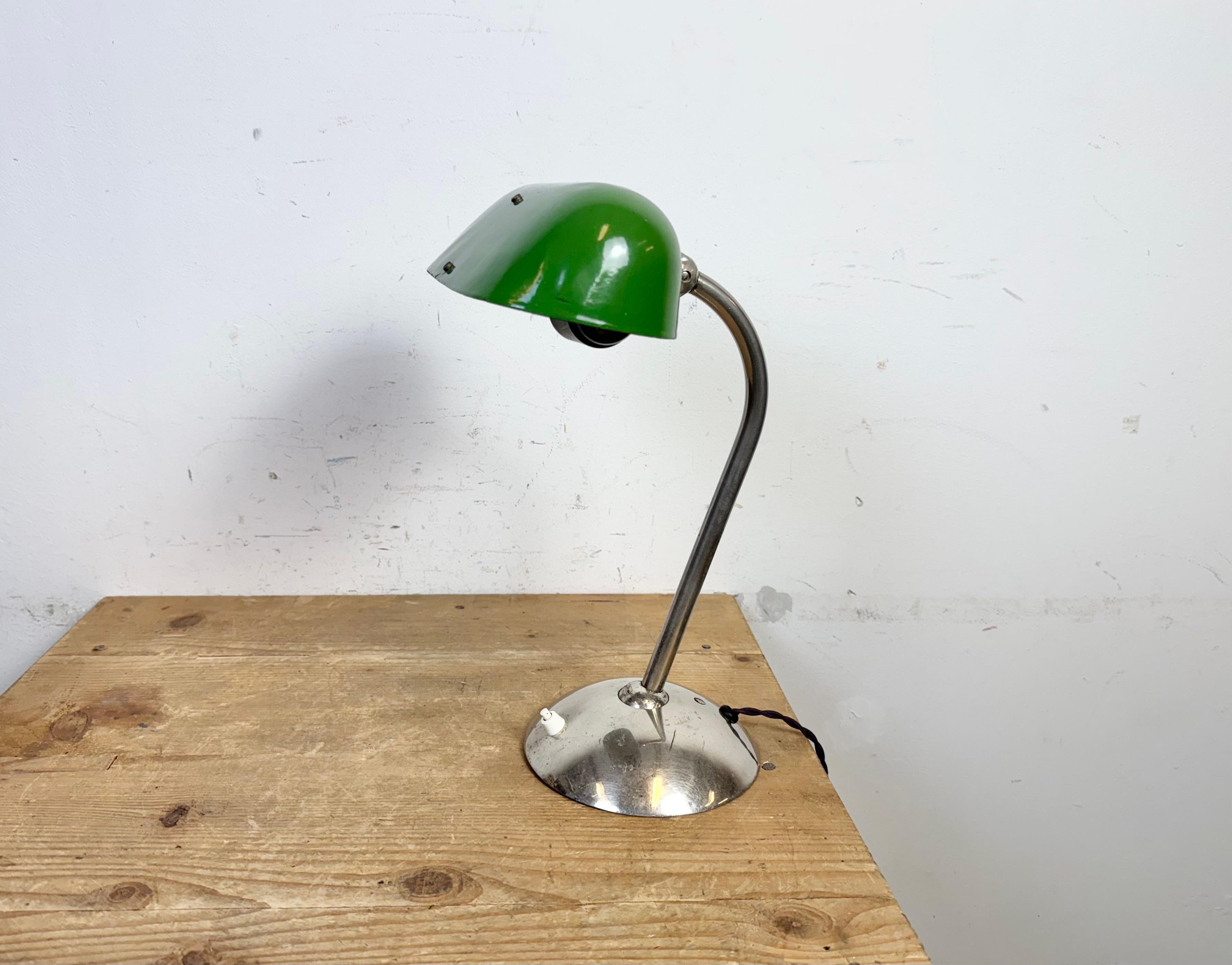 Questa lampada da tavolo verde è stata realizzata nell'ex Cecoslovacchia negli anni Cinquanta. Presenta un paralume in smalto verde con interno in smalto bianco e una base e un braccio in ferro cromato con due snodi regolabili. L'attacco in