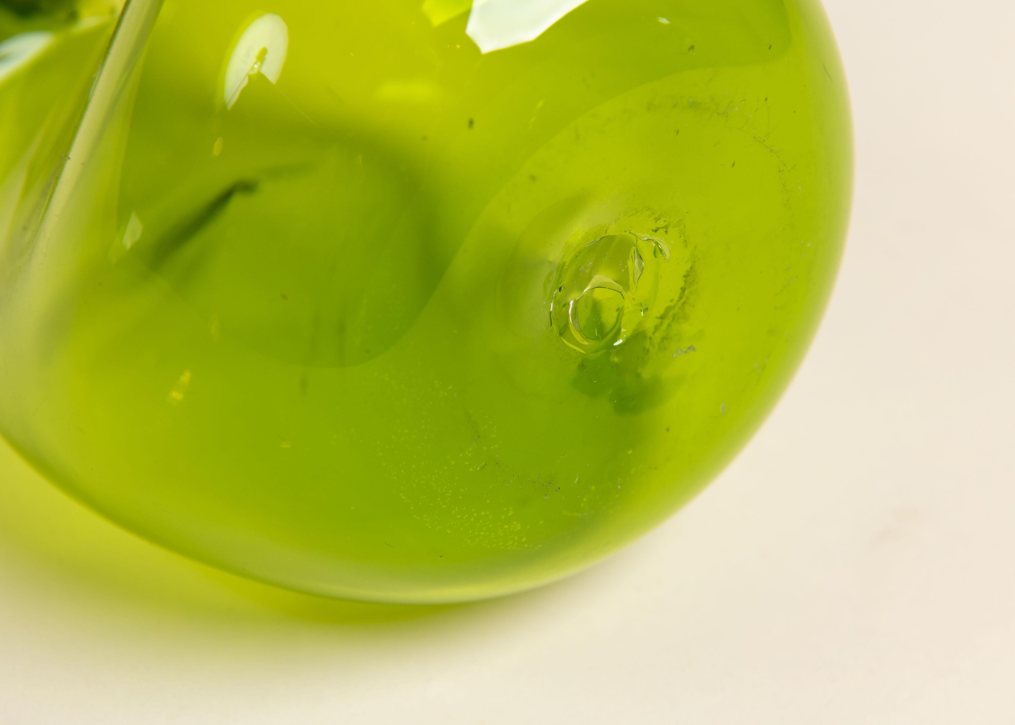 Carafe vintage en verre vert avec bouchon rond transparent. La forme organique de cette pièce en verre soufflé constitue un élément de style. Il est merveilleux seul ou en groupe sur un chariot de bar ou un buffet.