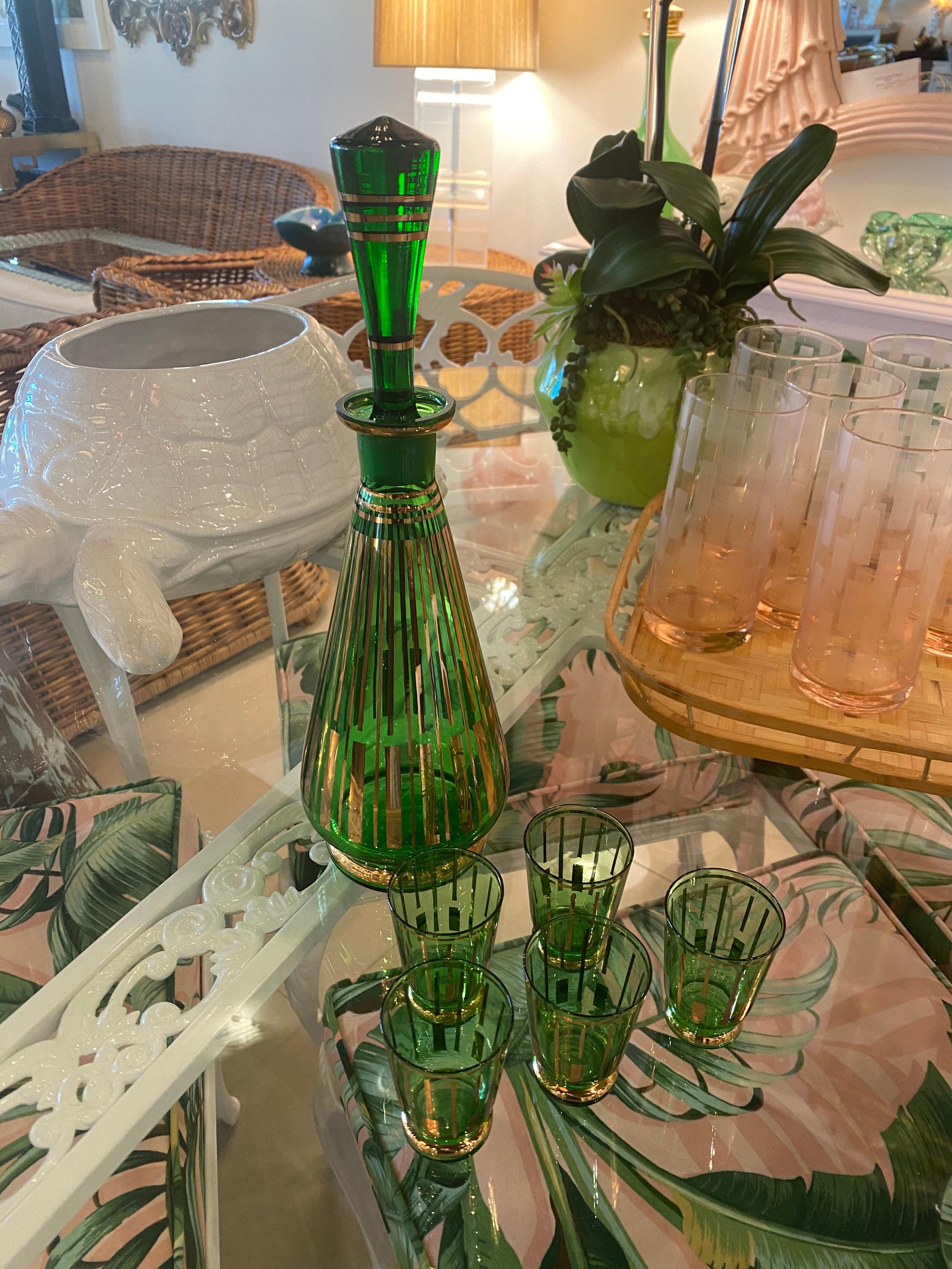Beautiful vintage 1950s green and gold glass decanter drinking set. Includes decanter with glass stopper and 5 shot glasses. No chips or breaks. Beautiful green color! 
Decanter 12.5 H x 3.5 D
Glasses 2.5 H.