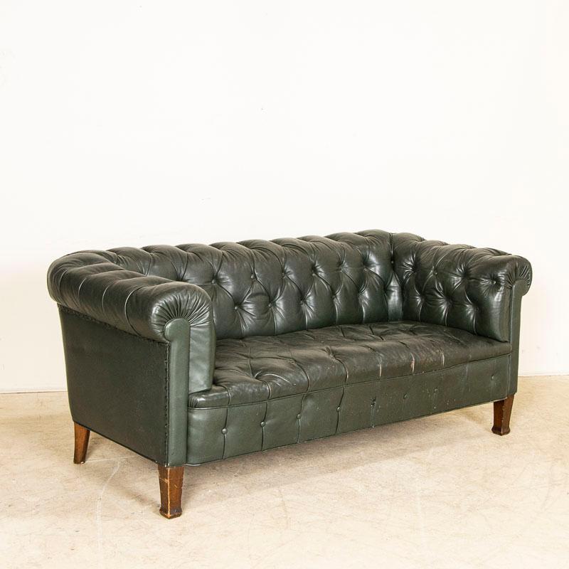 Vintage leather has an appeal all its own, even when worn and weathered such as this old single seat sofa. The heavily rolled arms and back are in the classic Chesterfield style (tufted with button accents), while the green leather makes it a unique