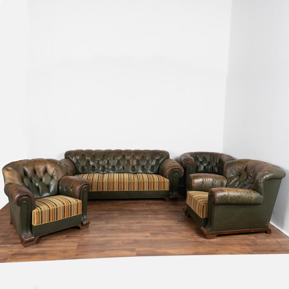 Set (4) vintage leather Chesterfield style sofa with heavily rolled arms, pair of arm chairs and additional barrel chair all resting on wood base/feet.
The dark green leather is tufted with buttons, several missing and loose.
Heavy years of use