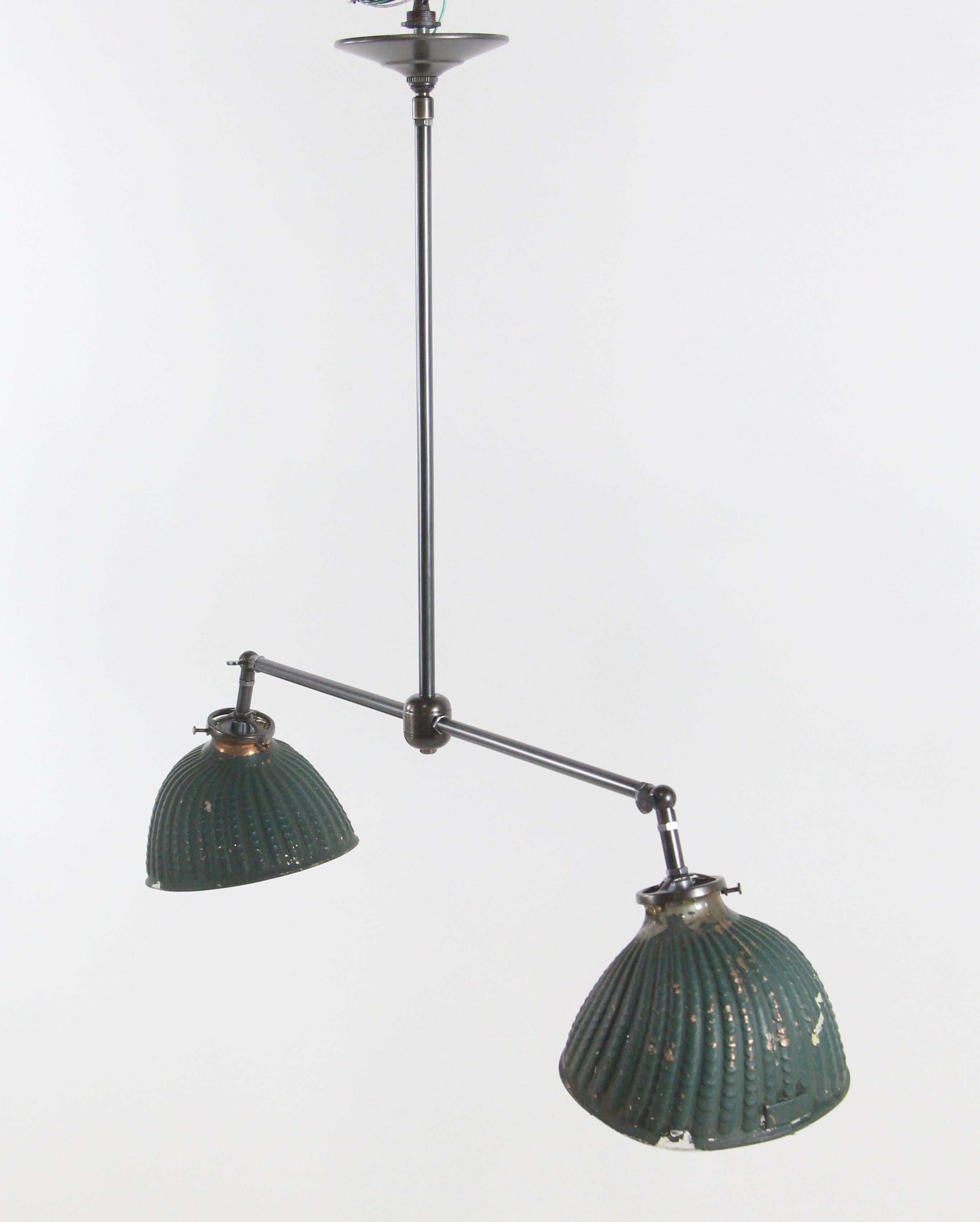 New modern brass double pendant light fixture with original 1920s green rippled X-ray glass shades. The insides of the shades are silvered glass. The arms are adjustable so that the shades can be set at the angle desired. Price includes restoration.
