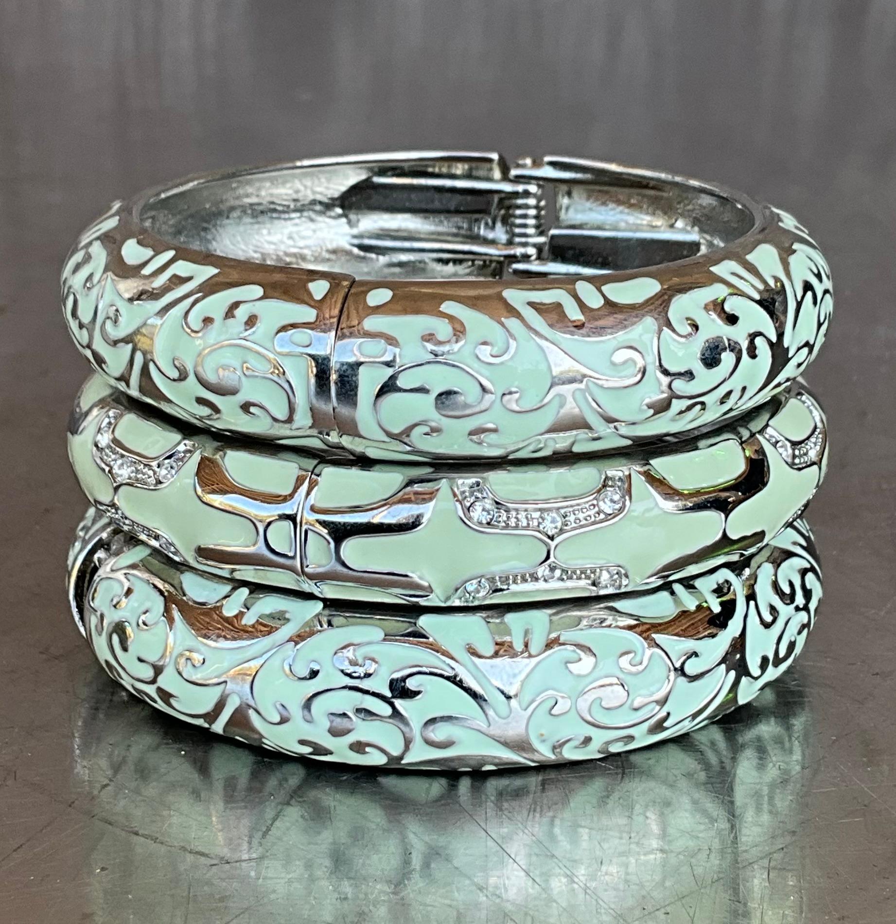 I bracciali con smalto verde e argento sono accessori senza tempo che aggiungono un tocco di eleganza a qualsiasi ensemble. Un set di tre bracciali di questo tipo offre versatilità, permettendo di impilarli o di indossarli singolarmente per