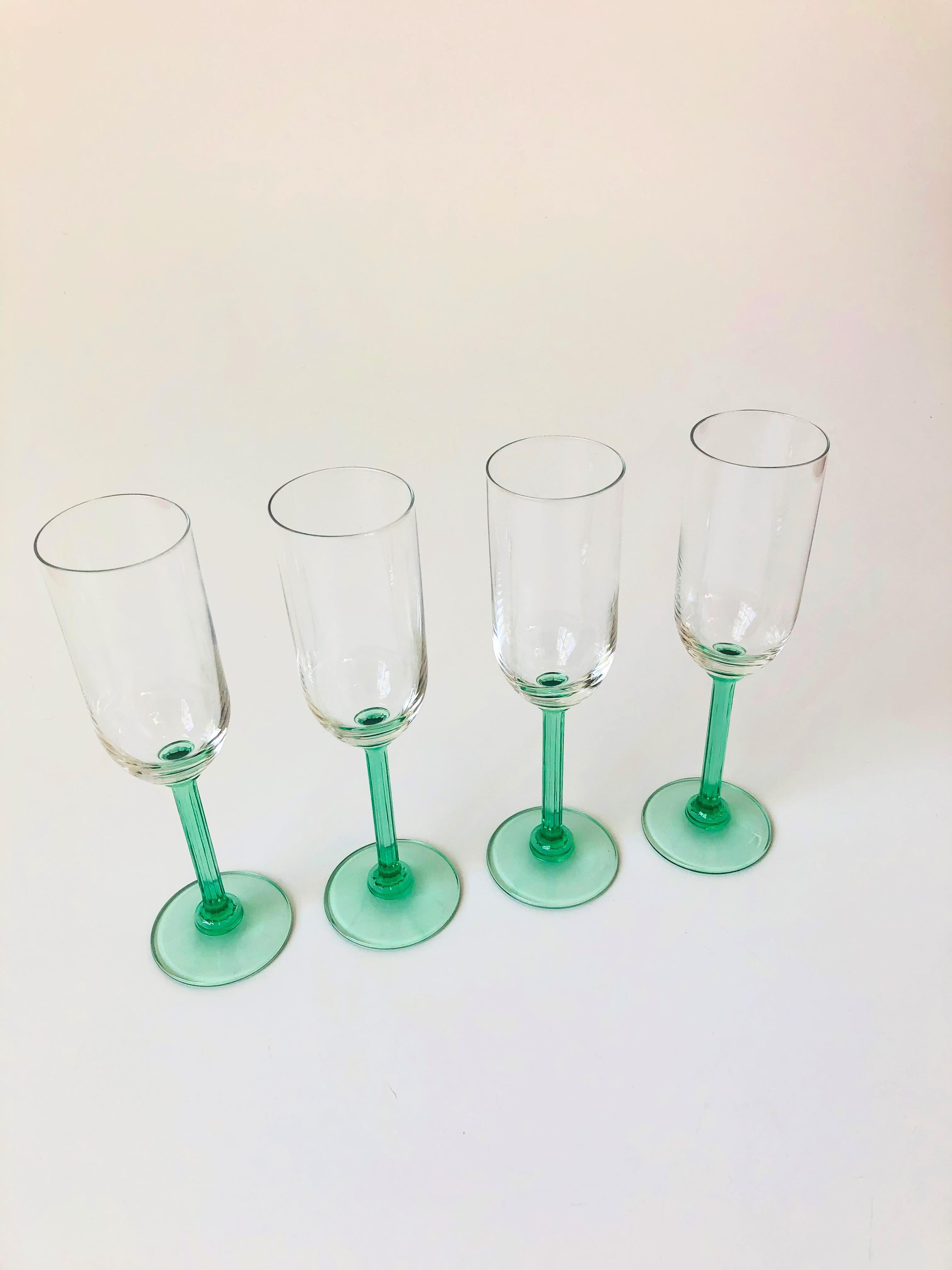A set of 4 vintage champagne flutes. Each with a beautiful textured pale green stem and a clear top.
    