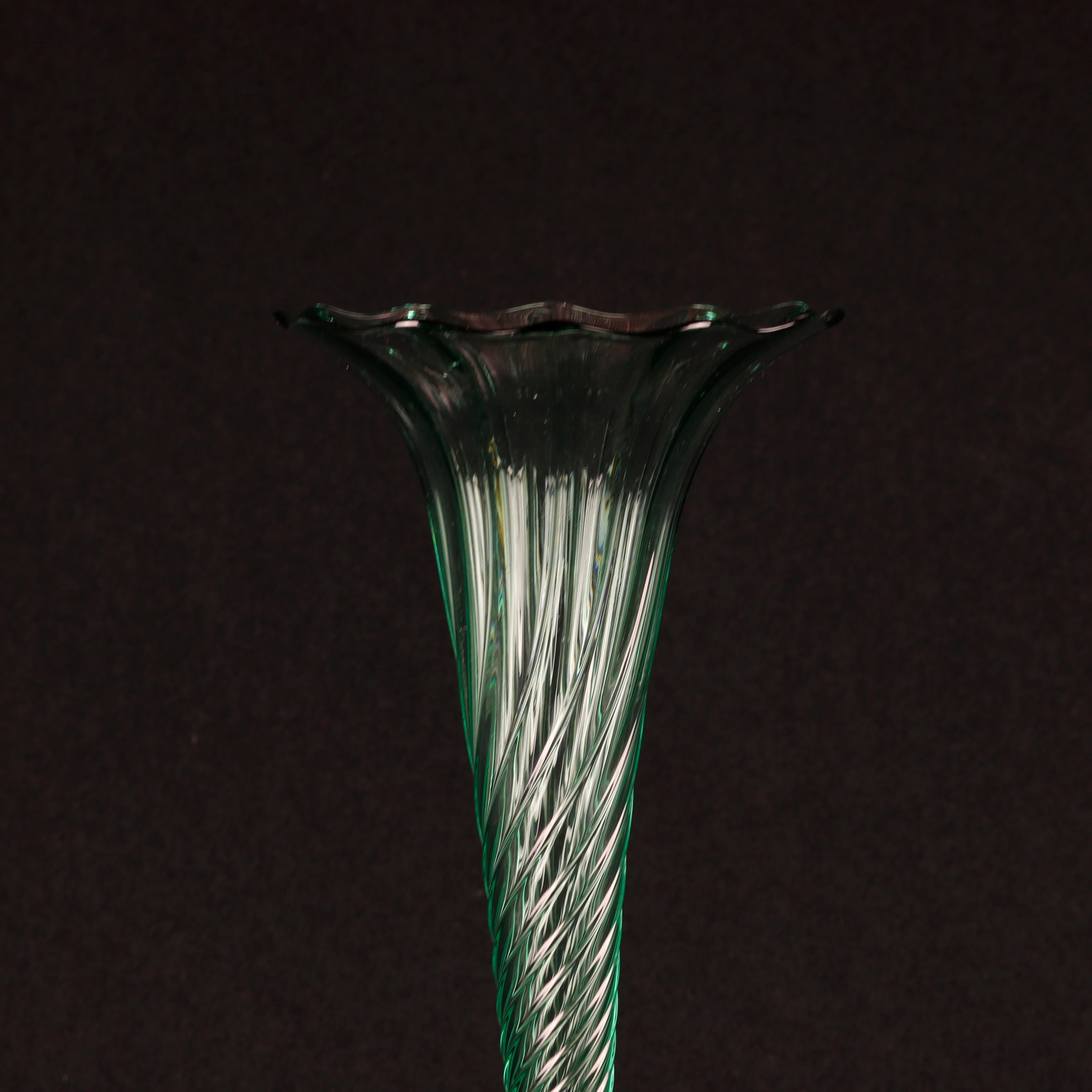 A vintage mouth blown art glass trumpet vase in the manner of Steuben offers swirled green glass in flared form with floral shaped rim, seated on colorless glass foot, unsigned, 20th century.

Measures: 10.25