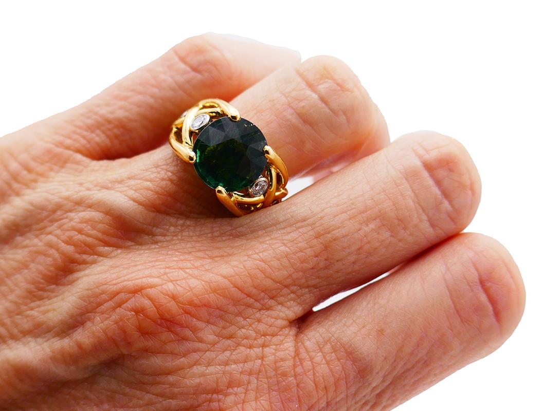 Classy ring featuring a 5.30-carat round faceted green tourmaline set in 18 karat yellow gold and accented with two on each side bezel set round brilliant cut diamonds (G-H color, VS clarity, 0.24 carat total weight). Diamonds are set in white