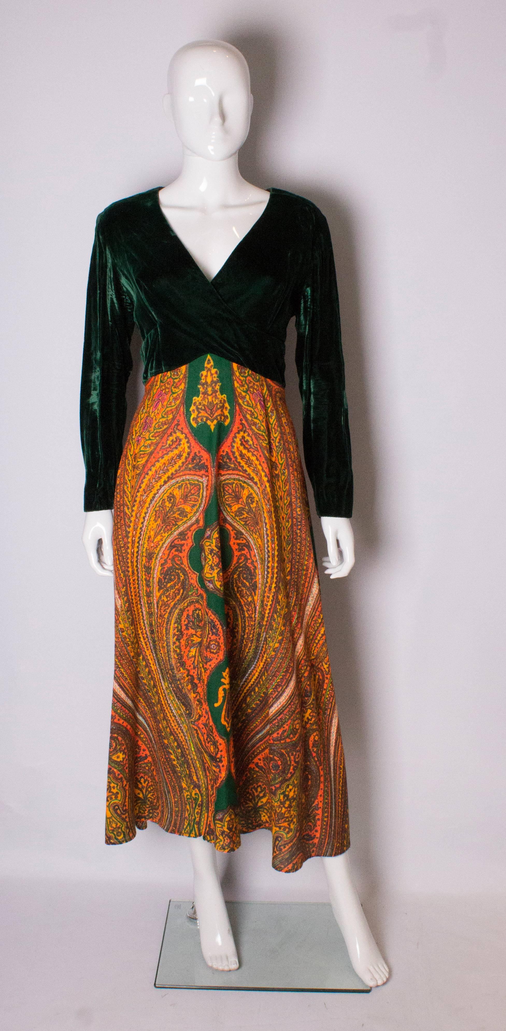 An easy to wear vintage gown. The dress has a green velvet top part with v cross over neckline. The skirt is an A line orange print.
