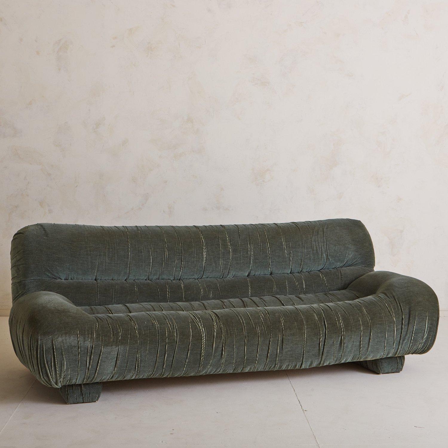 A vintage Italian sofa in original sage green velvet with beautiful ruched detailing. This sofa sits on two upholstered platform feet. We love the horizontal lines and delicate curves on this beauty. Sourced in Italy, 1970s.


