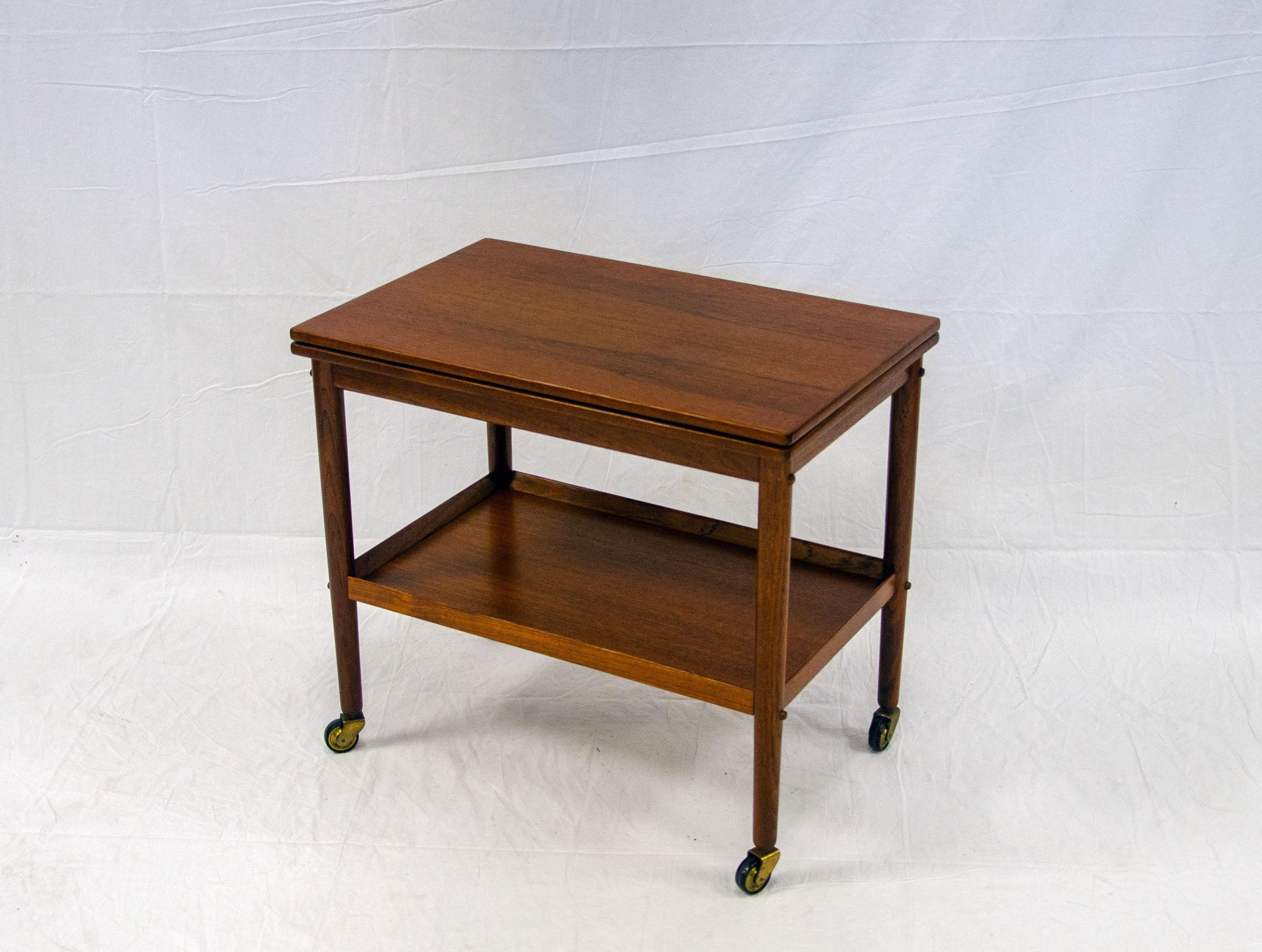 This Danish teak rolling cart has an expanding top that rotates on the base and flips open to make a 35 1/2