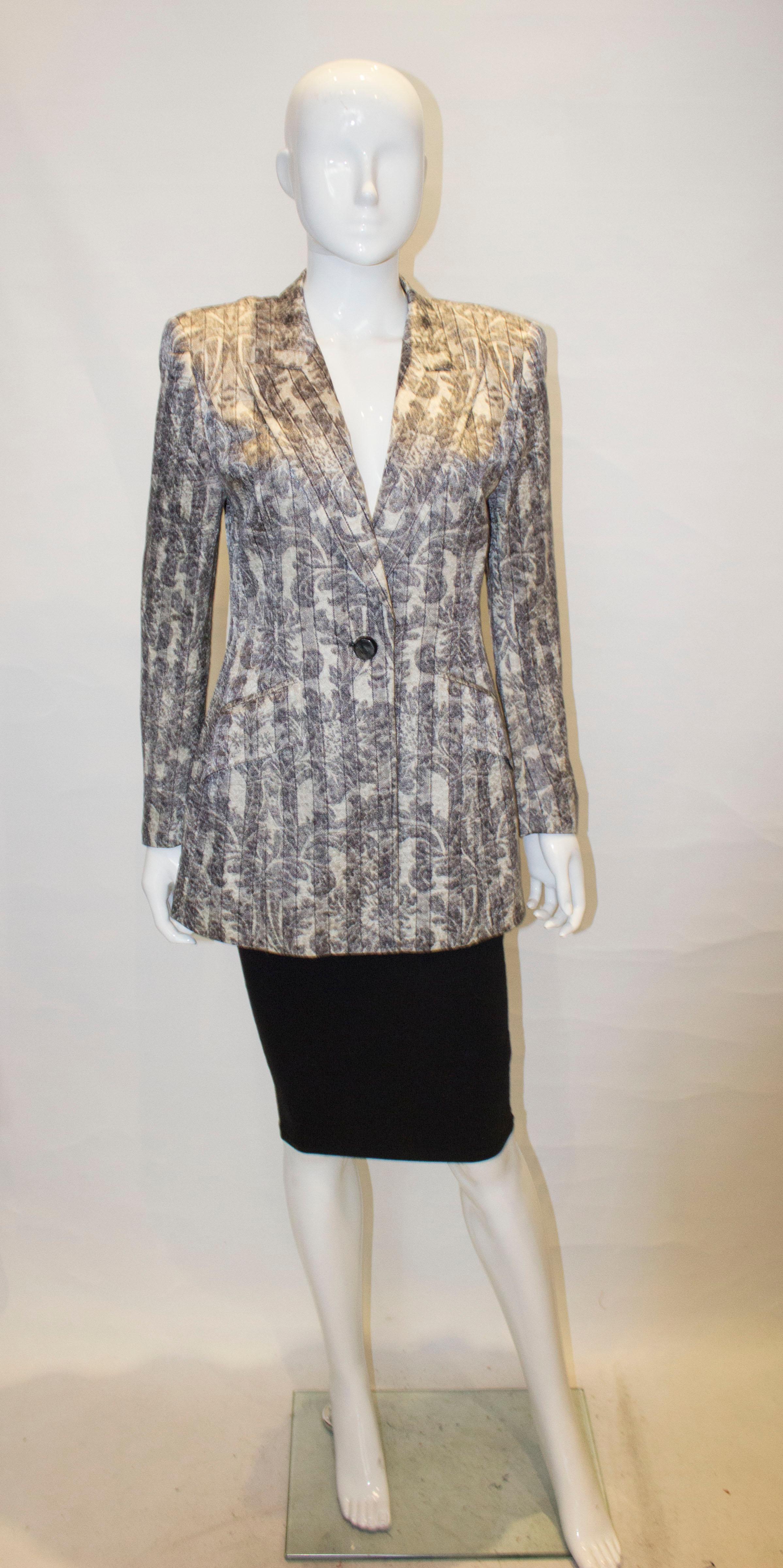 A pretty vintage jacket by Escada in a silk and wool mix. The jacket is in a light grey with a stripe and pattern design. It has a one button opening, two flap pockets and is fully lined.