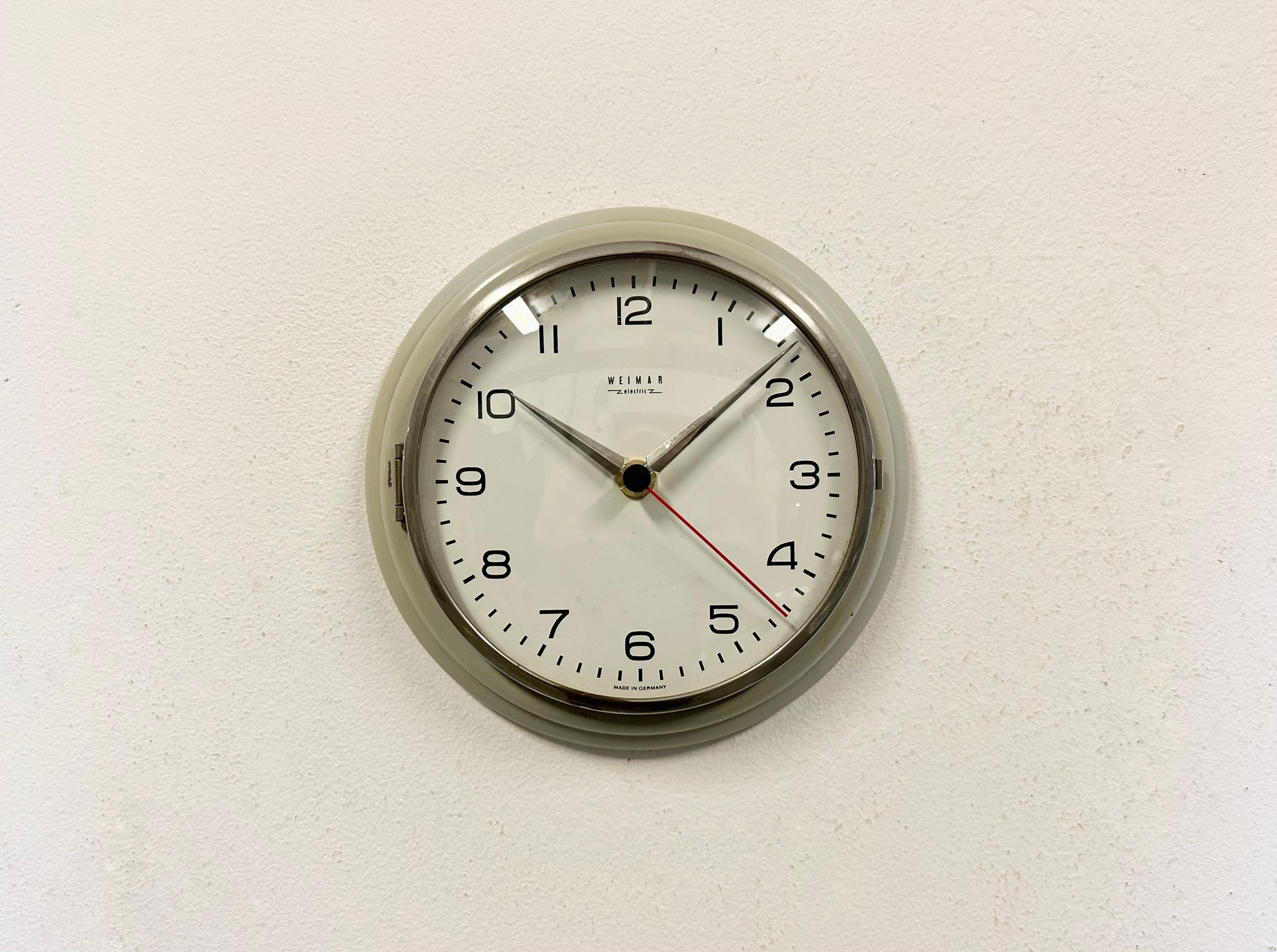 Vintage Industrial wall clock produced by Weimar in former East Germany during the 1970s. It features a grey iron frame, a metal dial, an aluminium hands and a curved clear glass cover. The battery-powered clockwork requires one AA battery.