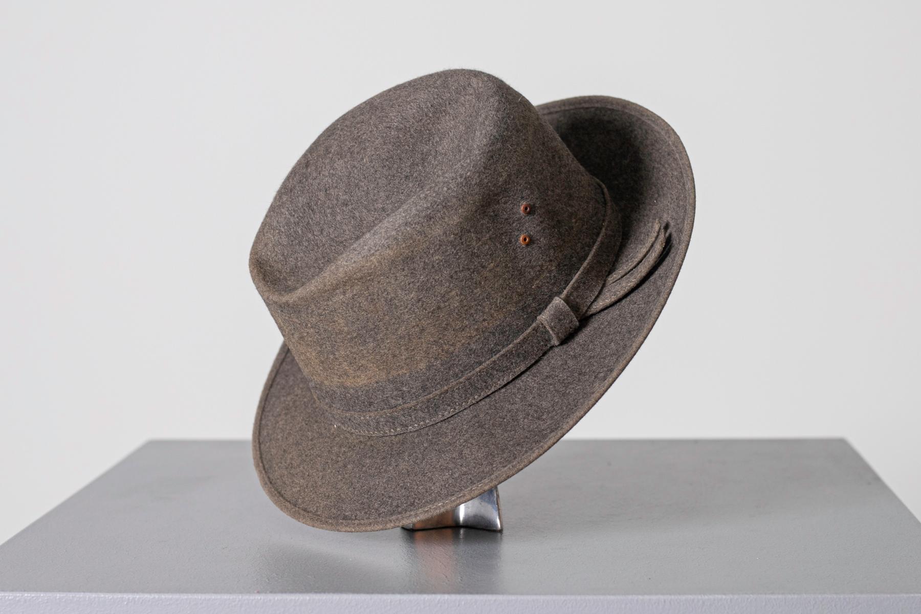 Joli chapeau en feutre gris du millésime 1990, belle fabrication italienne.
Le chapeau est entièrement réalisé en feutre
Le dôme porte 4 pinces douces.
À la base extérieure du dôme se trouve une bande grise avec un arc minimal sur la gauche.
À