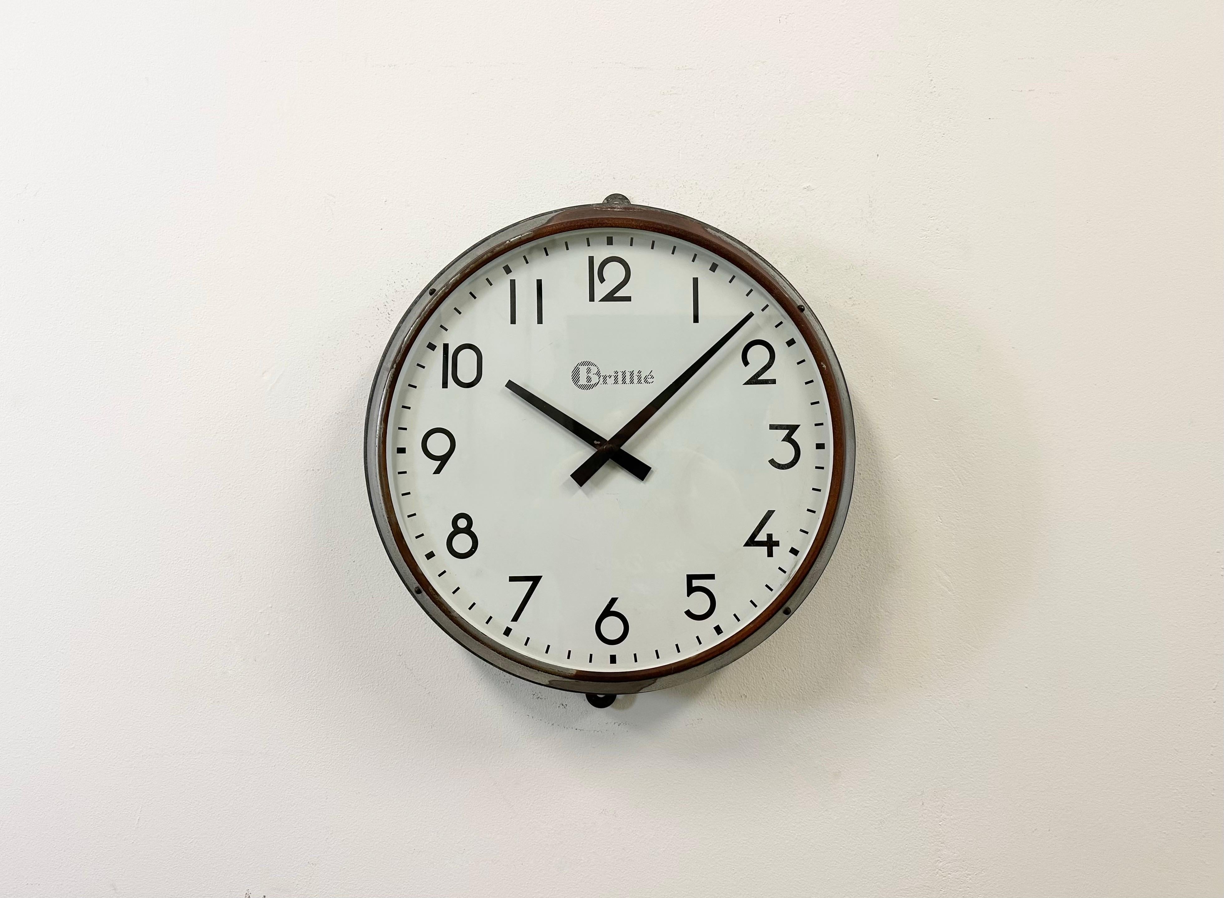 This wall clock was produced by Brillié in France during the 1950s. It features a grey metal case, an iron dial and a clear glass cover. The piece has been converted into a battery-powered clockwork and requires only one AA-battery. The weight of