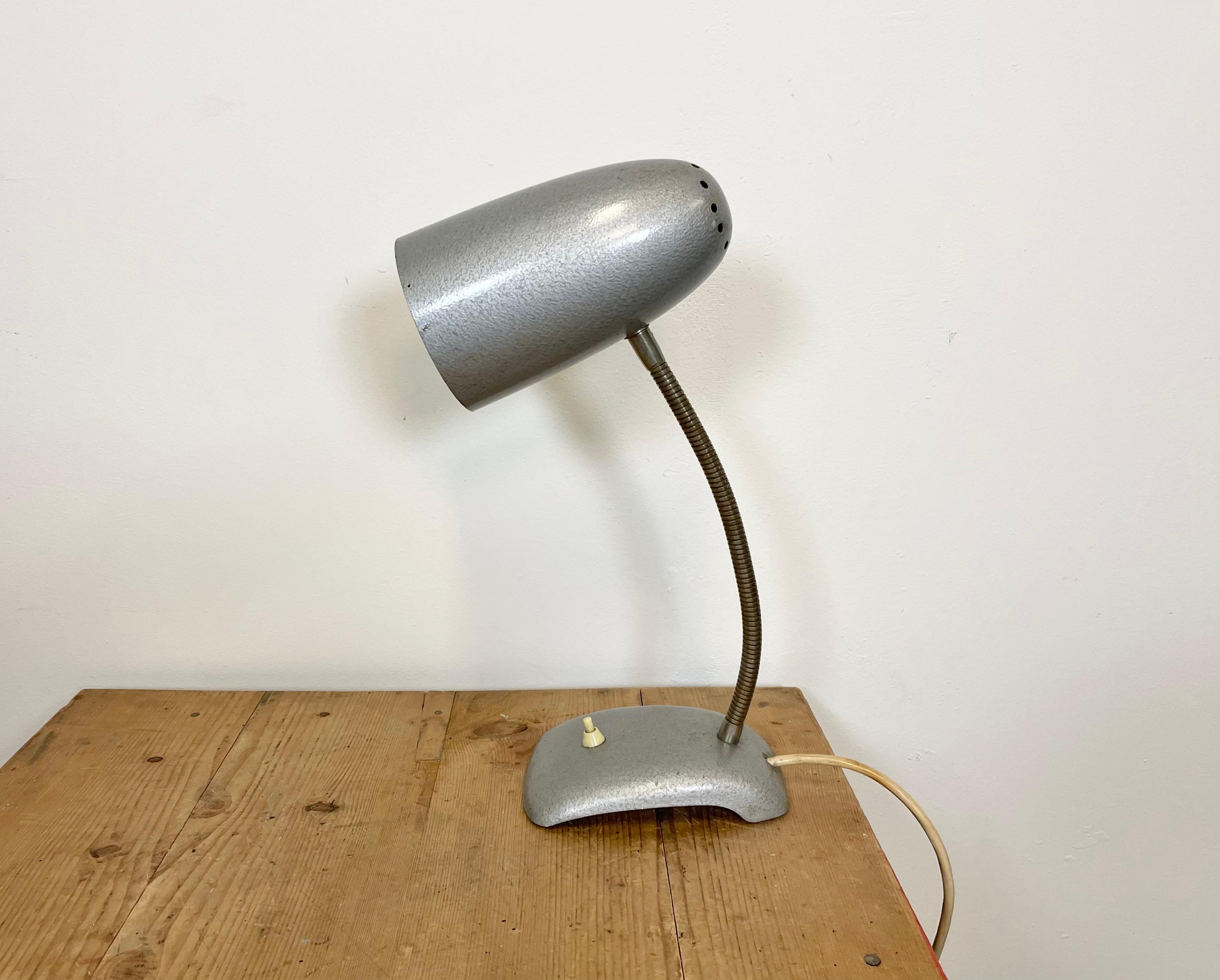 Industrial table lamp made in former Czechoslovakia during the 1960s. It features a grey hammer paint body and a chrome plated gooseneck. The socket requires E 27 light bulbs. Very good vintage condition. The lampshade diameter is 11 cm.