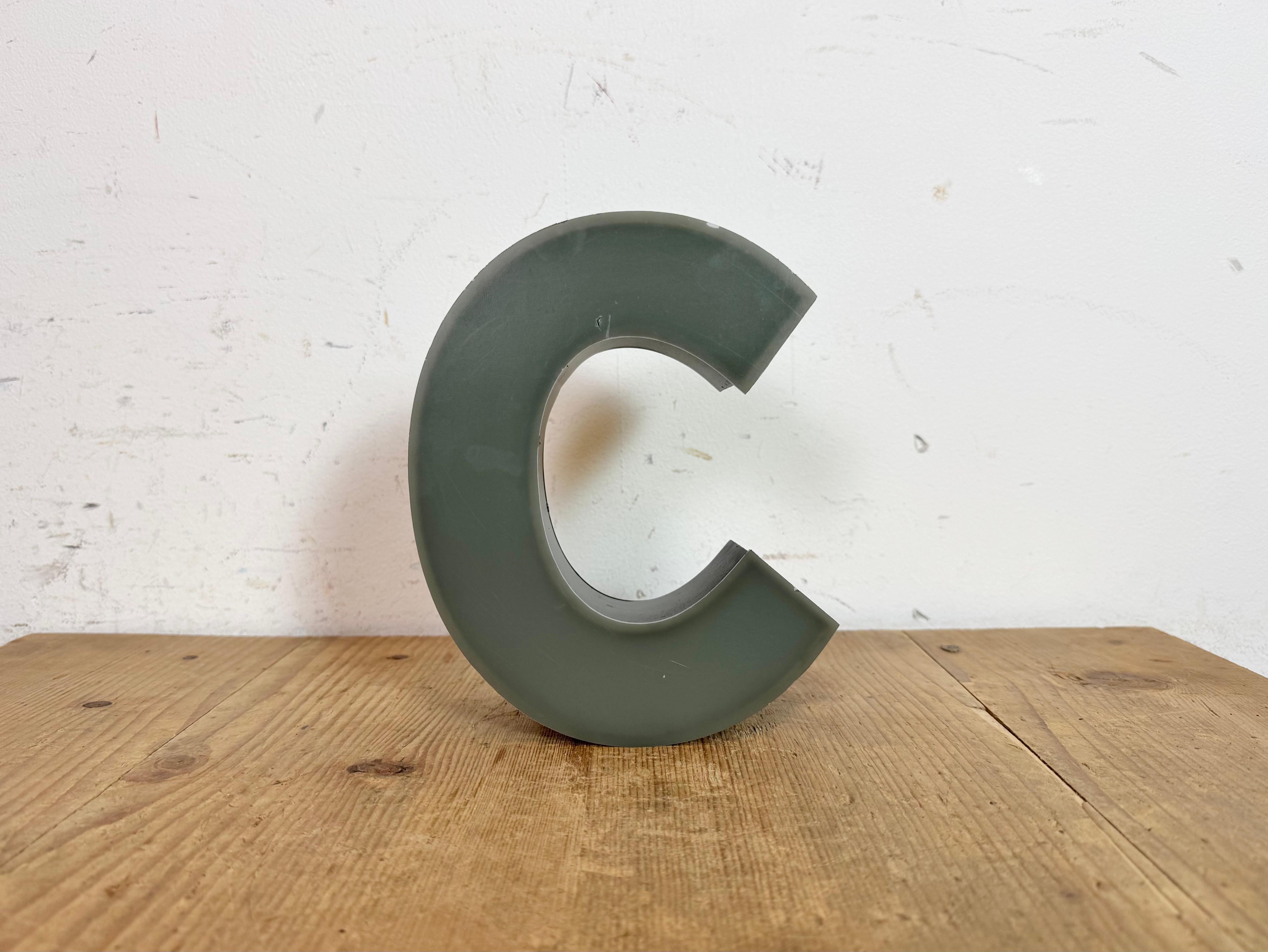 This vintage industrial illuminated letter “ c “ was made in Germany during the 1970s and comes from an old advertising banner. It features a black metal body and a grey plastic cover. It is equipped with a LED strip. The letter can be used as a