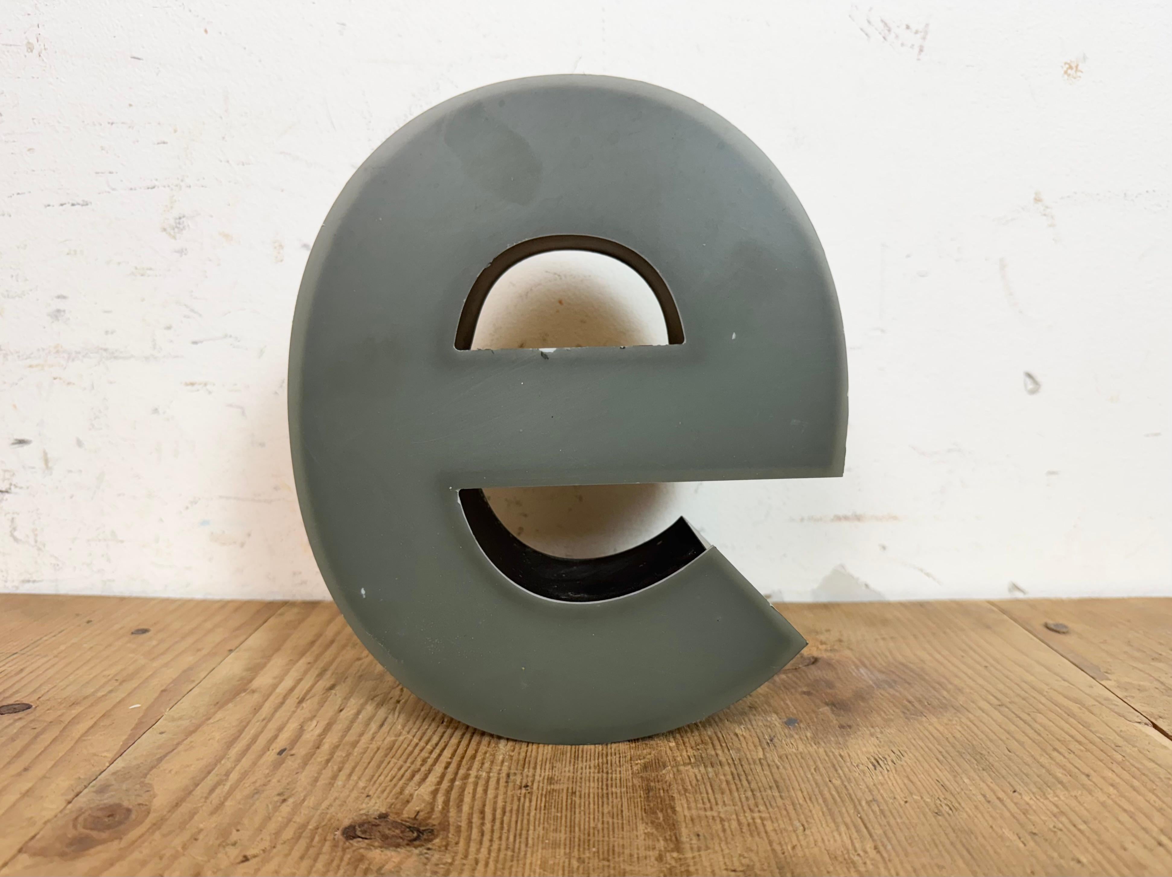 This vintage industrial illuminated letter “ e “ was made in Germany during the 1970s and comes from an old advertising banner. It features a black metal body and a grey plastic cover. It is equipped with a LED strip. The letter can be used as a