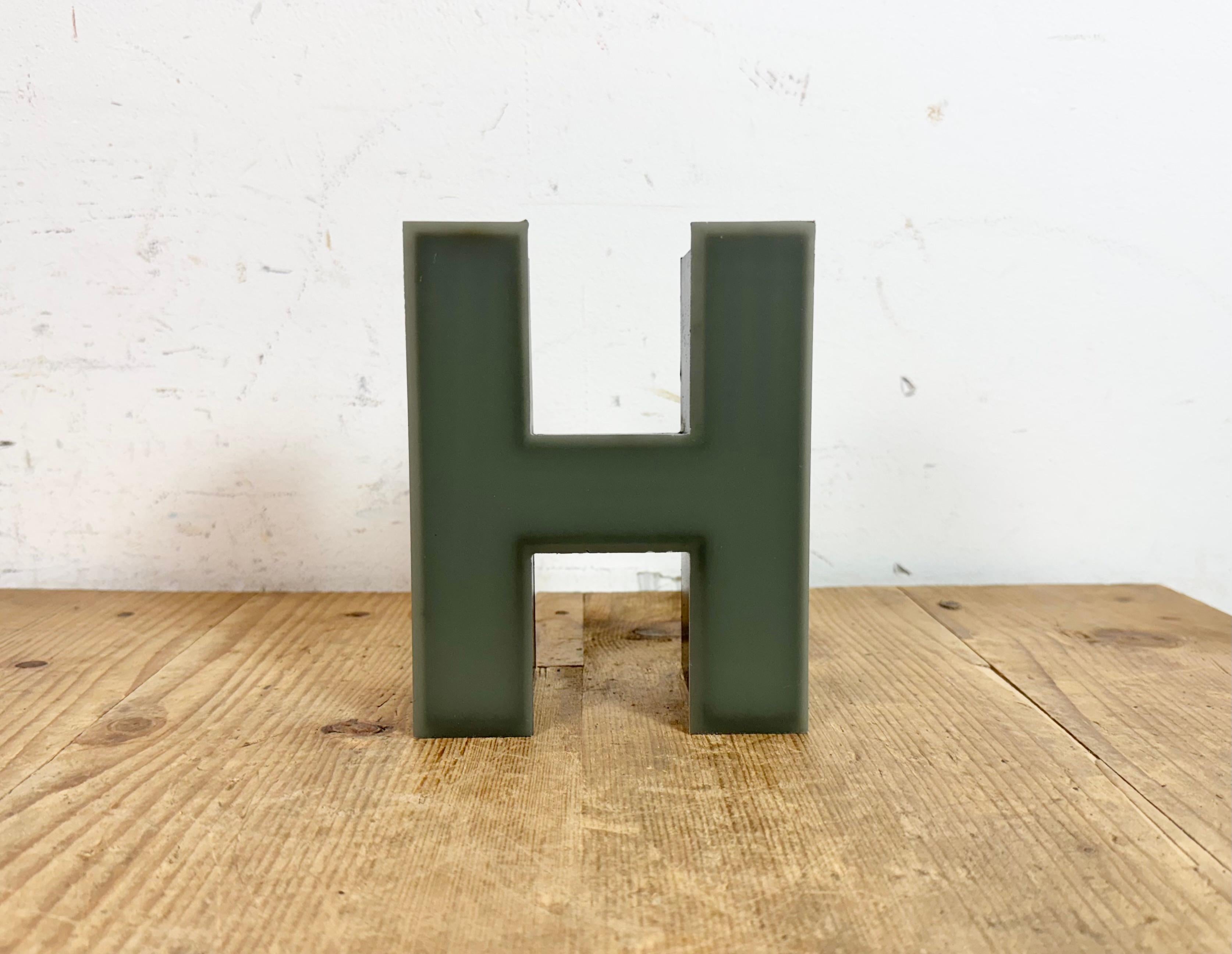This vintage industrial illuminated letter “ H “ was made in Germany during the 1970s and comes from an old advertising banner. It features a black metal body and a grey plastic cover. It is equipped with a LED strip. The letter can be used as a