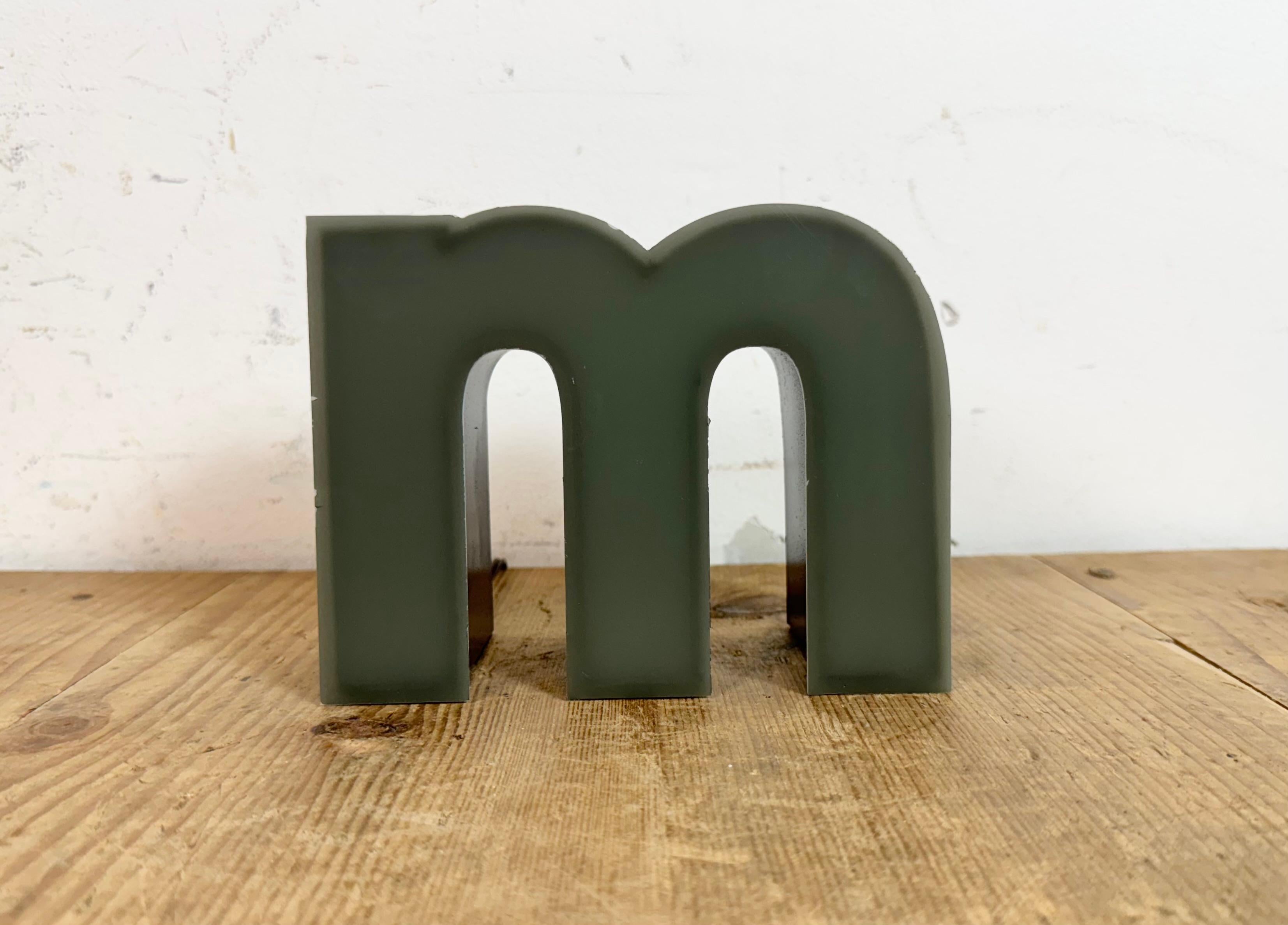 This vintage industrial illuminated letter “ m “ was made in Germany during the 1970s and comes from an old advertising banner. It features a black metal body and a grey plastic cover. It is equipped with a LED strip. The letter can be used as a