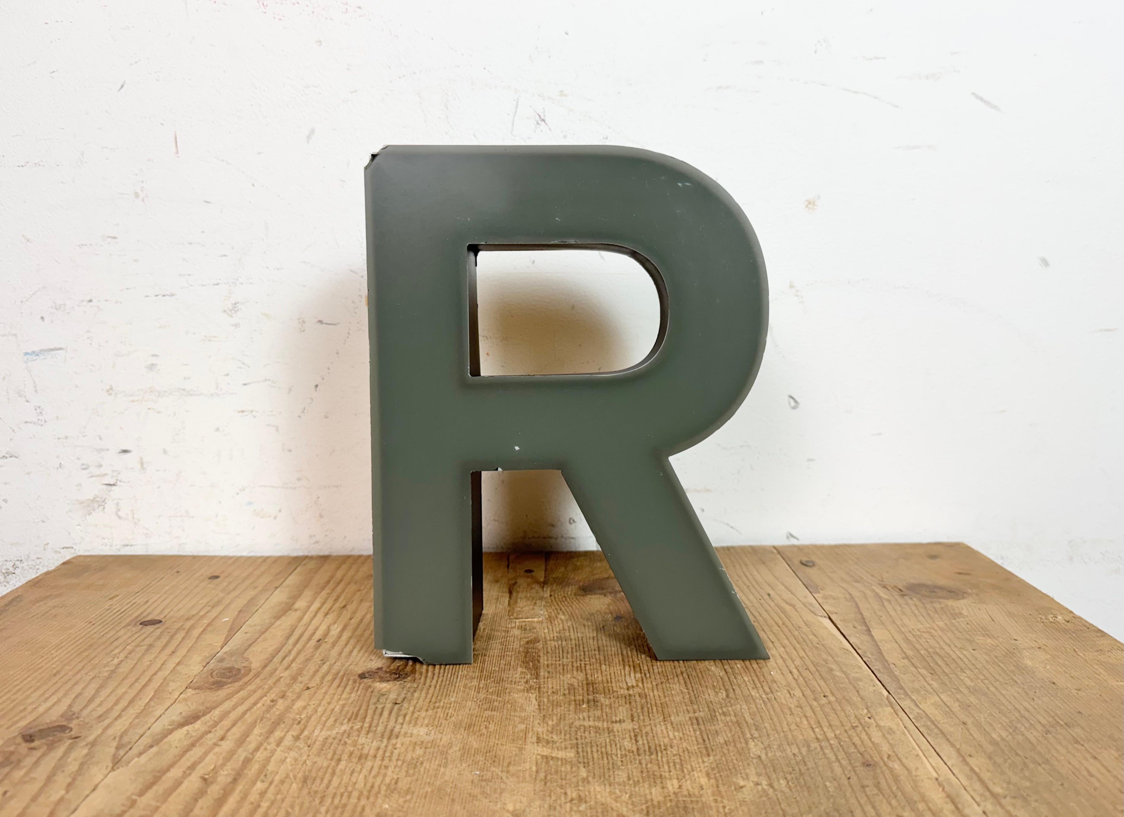 This vintage industrial illuminated letter “ R “ was made in Germany during the 1970s and comes from an old advertising banner. It features a black metal body and a grey plastic cover. It is equipped with a LED strip. The letter can be used as a
