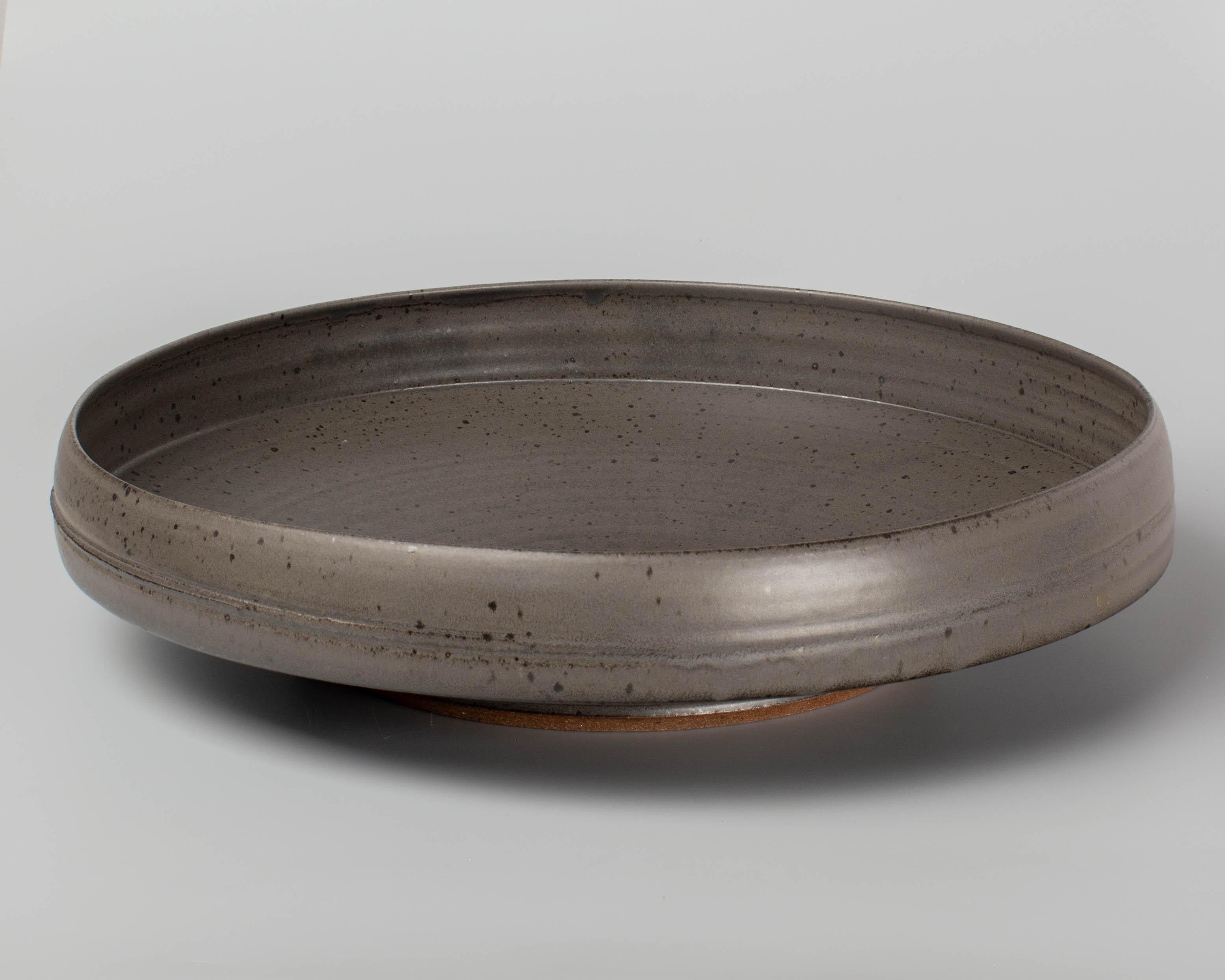 Una grande ciotola da centrotavola in studio Pottery del Mid Century Modern con smalto grigio opaco luminoso. Firma sul lato inferiore illeggibile. Circa 1960-1980. 
Dimensioni: 4 