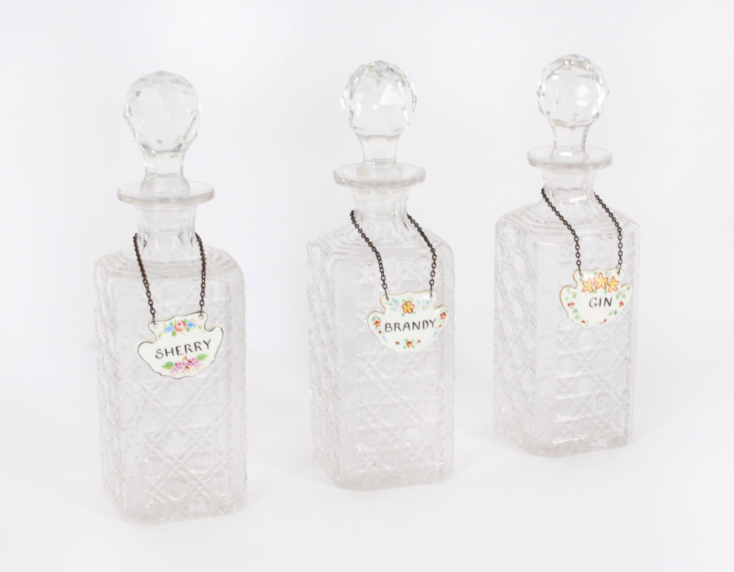 Superbe ensemble de trois carafes carrées et bouchons en cristal taillé, avec des labels en porcelaine portant l'inscription 