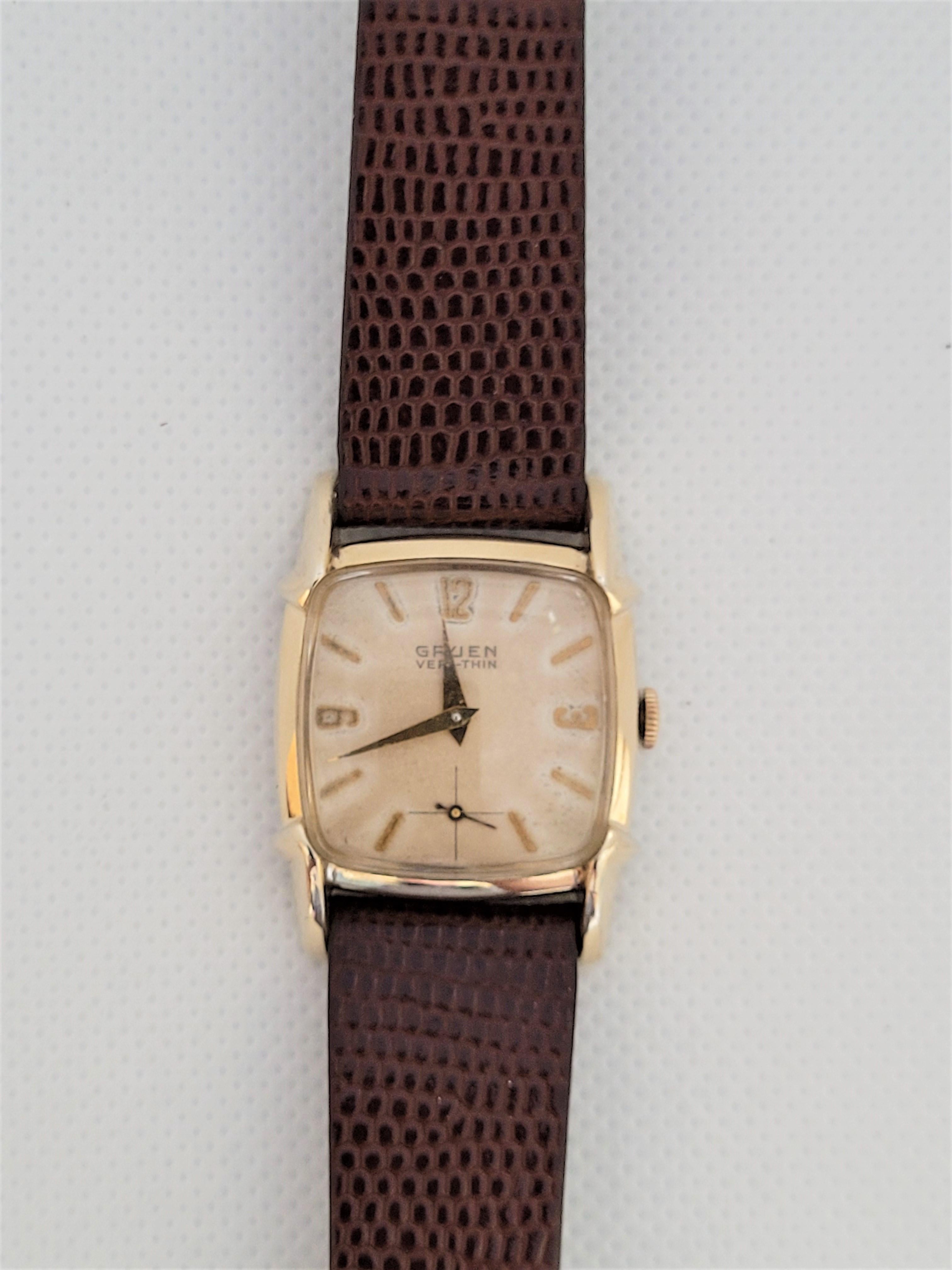 Vintage Gruen Veri-Thin watch with a 26mm x 26mm (10mm thick) square case that's 10kt rolled gold plated, champagne face with accent gold numerals. The plexiglass crystal is very clean and the face has slight discoloration due to age but is in good